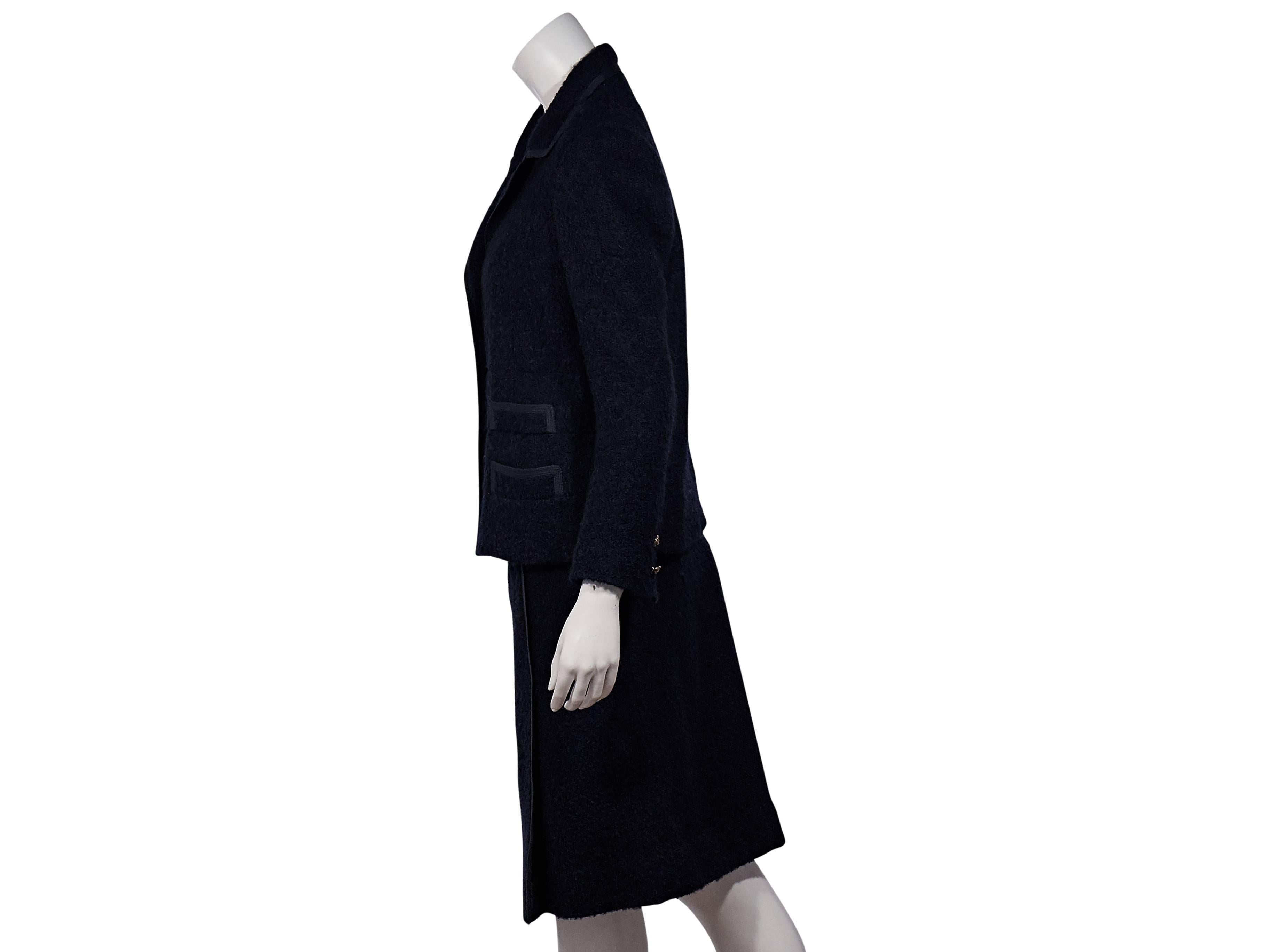 Product details: Navy marled wool two-piece suit set by Chanel. Notched lapel. Long sleeves. Double-button detail at cuffs. Button-front closure. Goldtone hardware. Matching faux wrap skirt. Banded waist. A-line silhouette. 
Condition: Excellent.