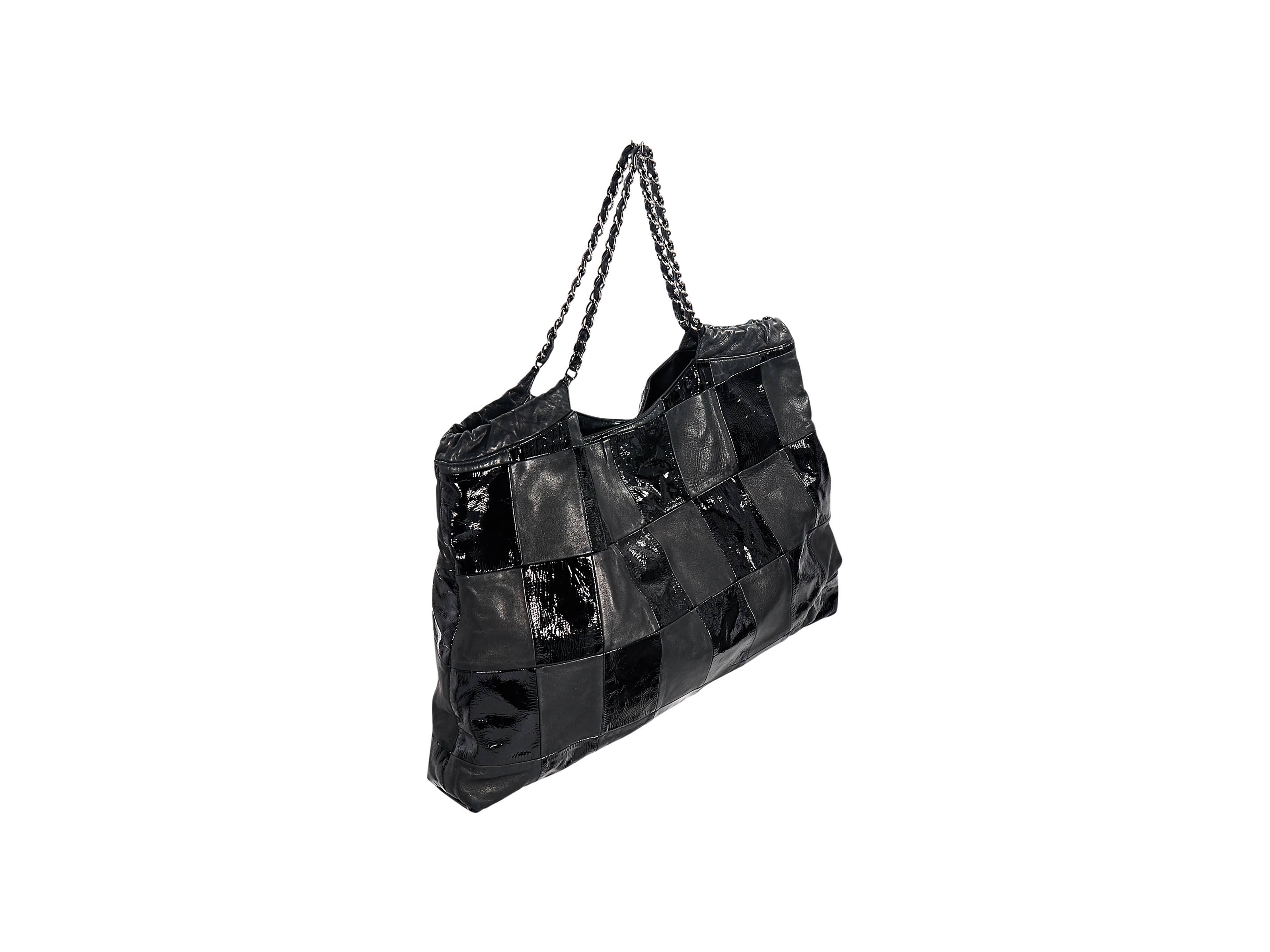 Product details:  Black leather Brooklyn Cabas tote bag by Chanel.  Patchwork leather and patent leather design.  Chain shoulder straps.  Magnetic snap closure.  Lined interior with inner slide and zip pockets plus key fob.  21