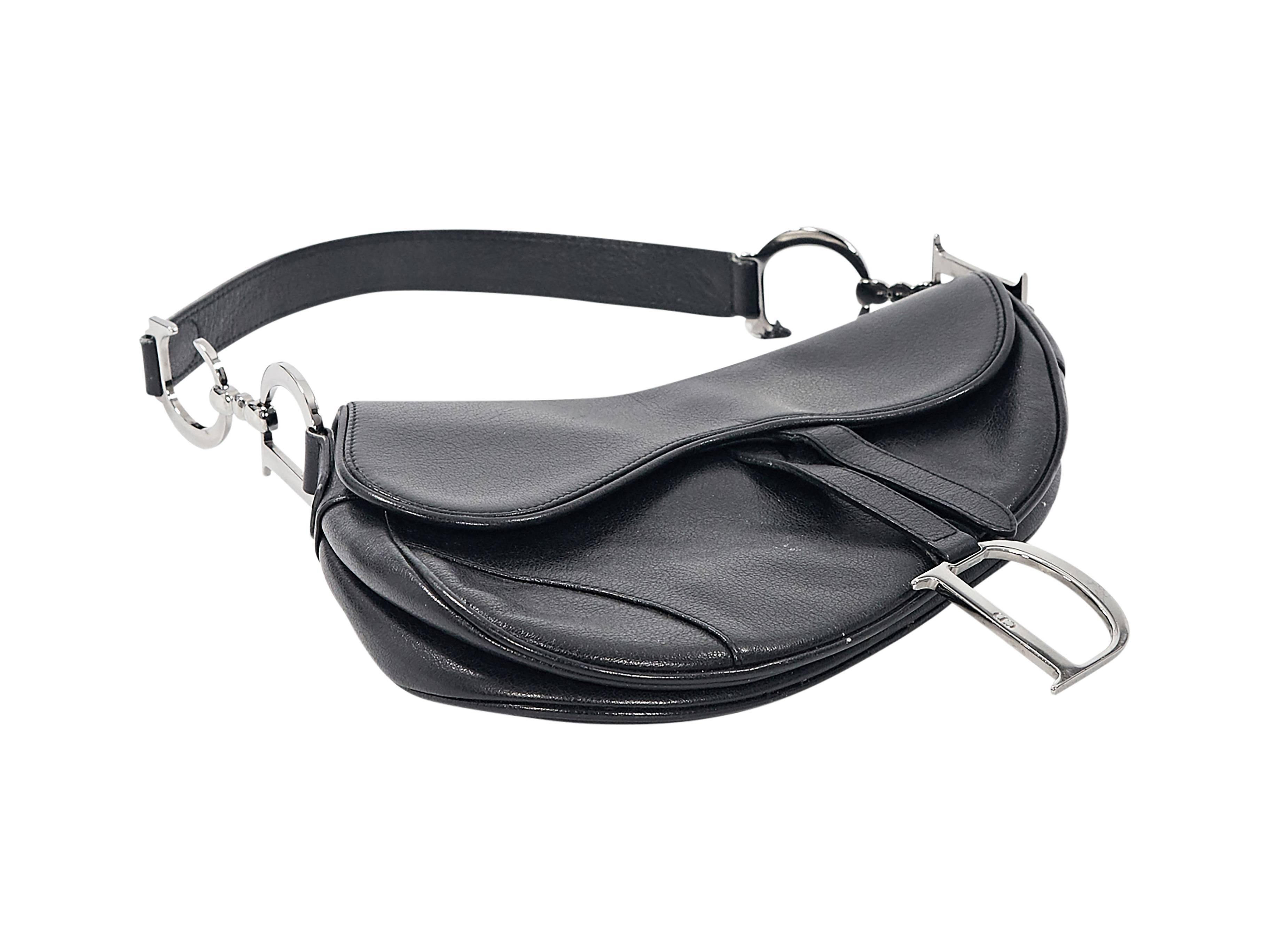 Product details: Black leather saddle bag by Christian Dior. Single shoulder strap. Front flap with Velcro strap closure. Lined interior with inner zip pocket. Back exterior slide pocket. Gunmetal-tone hardware. 10