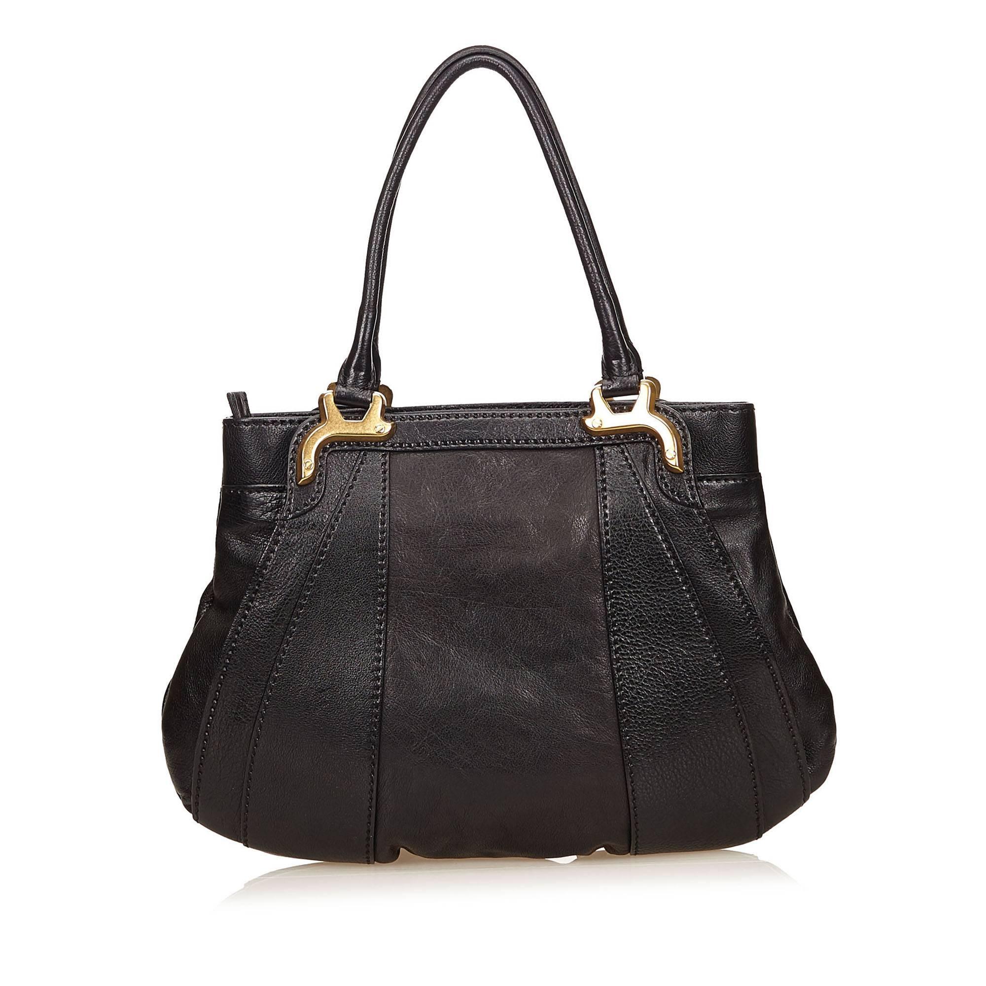 Product details:  Black leather and fabric shoulder bag by Valentino.  Accented with floral applique at front.  Dual shoulder straps.  Top zip closure.  Lined interior with inner zip pocket.  Goldtone hardware.  14