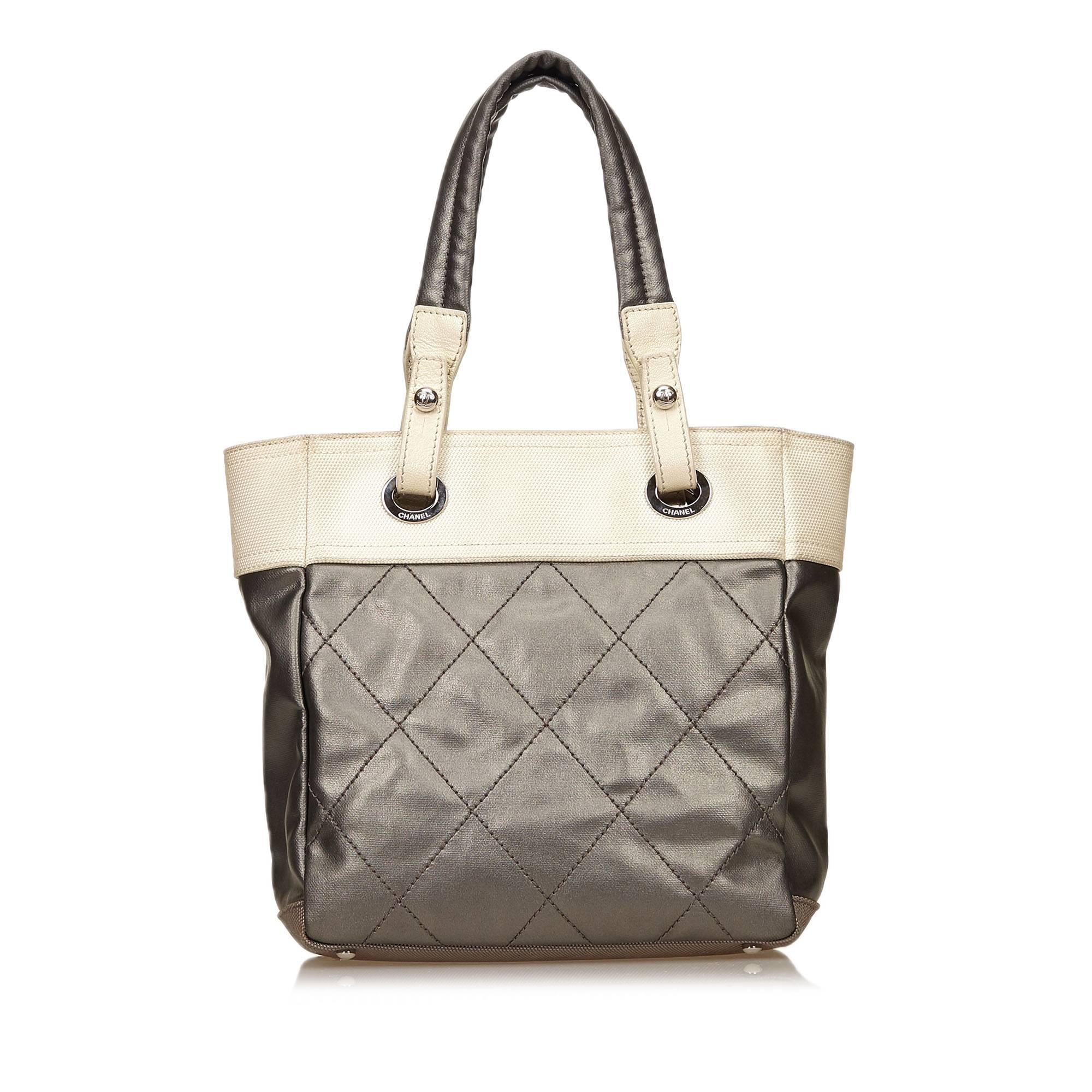 Product details:  Grey and ivory quilted coated canvas and fabric Paris Biarritz tote bag by Chanel.  Dual shoulder straps.  Top zip closure.  Lined interior with inner zip and open pockets with attached key fob.  Protective metal feet.  Silvertone