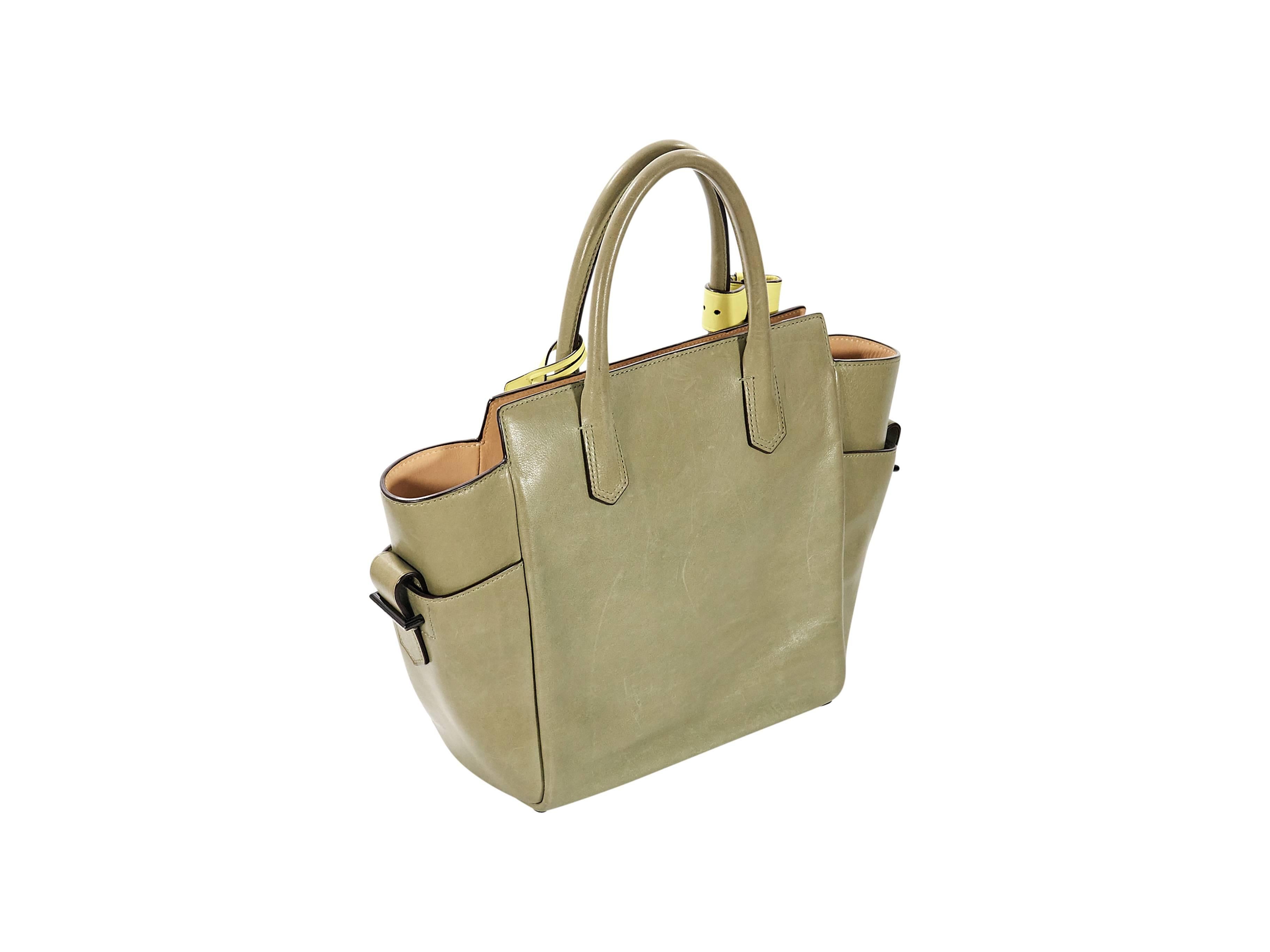 Product details:  Green mini Atlantique leather satchel by Reed Krakoff.  Top carry handles.  Open top.  Front exterior slide pocket.  Lined interior with inner zip pockets.  Side exterior buckle pockets.  14.5