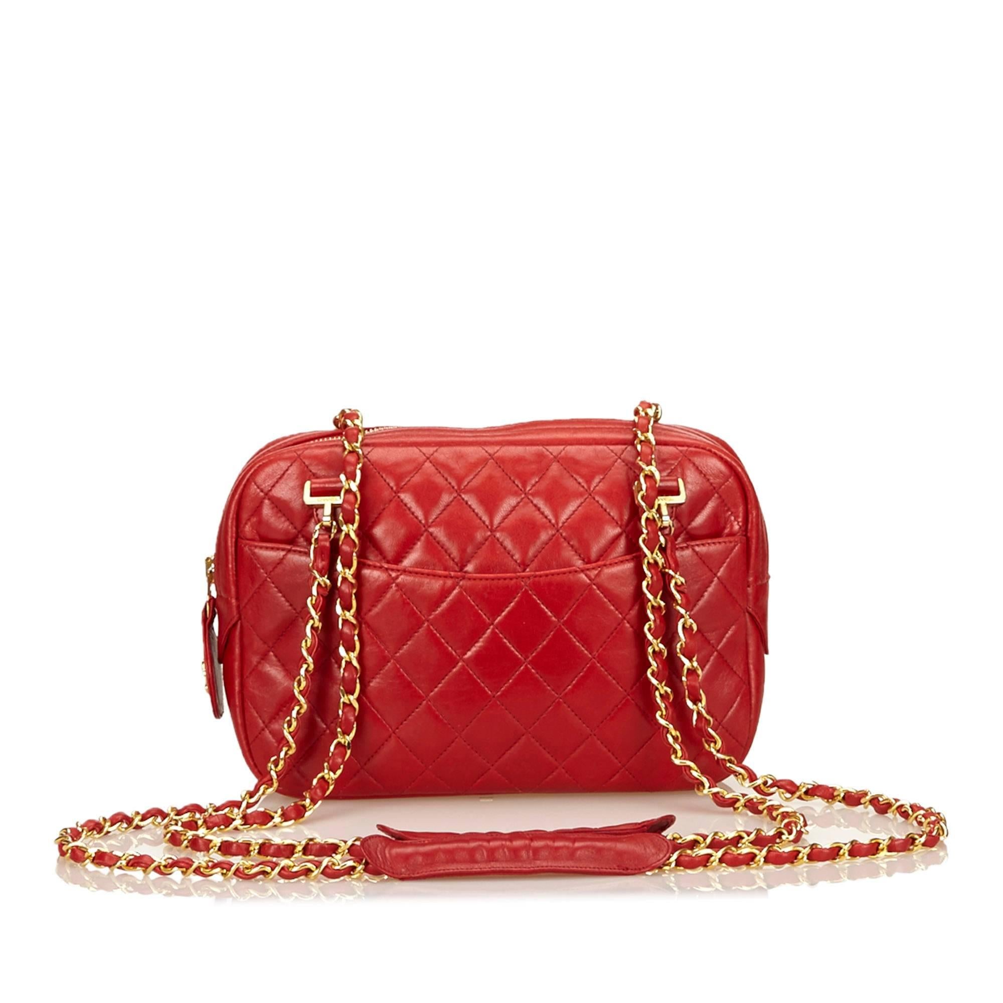 Product details:  Red quilted lambskin leather shoulder bag by Chanel.  Dual woven leather chain shoulder straps.  Top zip closure.  Lined interior with inner slide and zip pockets.  Front and back exterior slide pockets.  Goldtone hardware. 