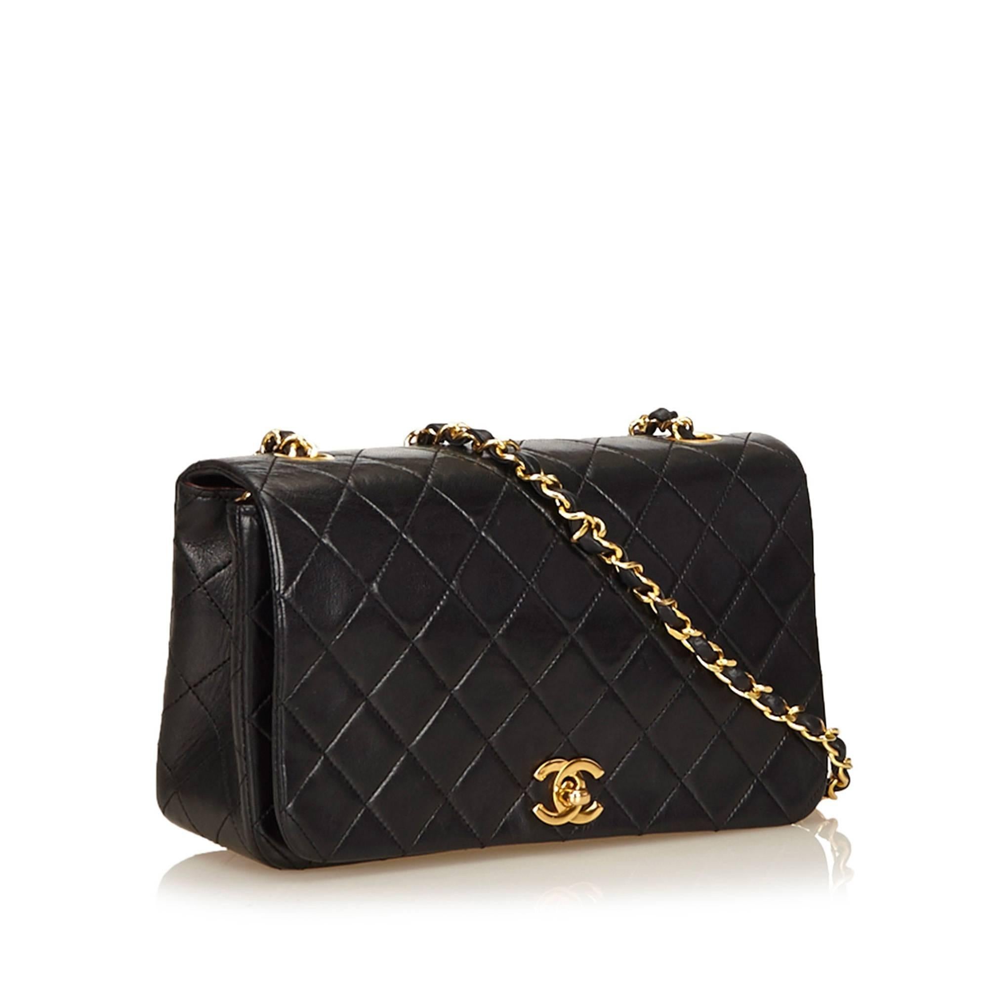 Product details:  Black quilted lambskin leather shoulder bag by Chanel.  Leather woven chain shoulder strap.  Front flap.  CC twist-lock closure.  Leather lined interior with inner zip and slide pockets.  Goldtone hardware.  9