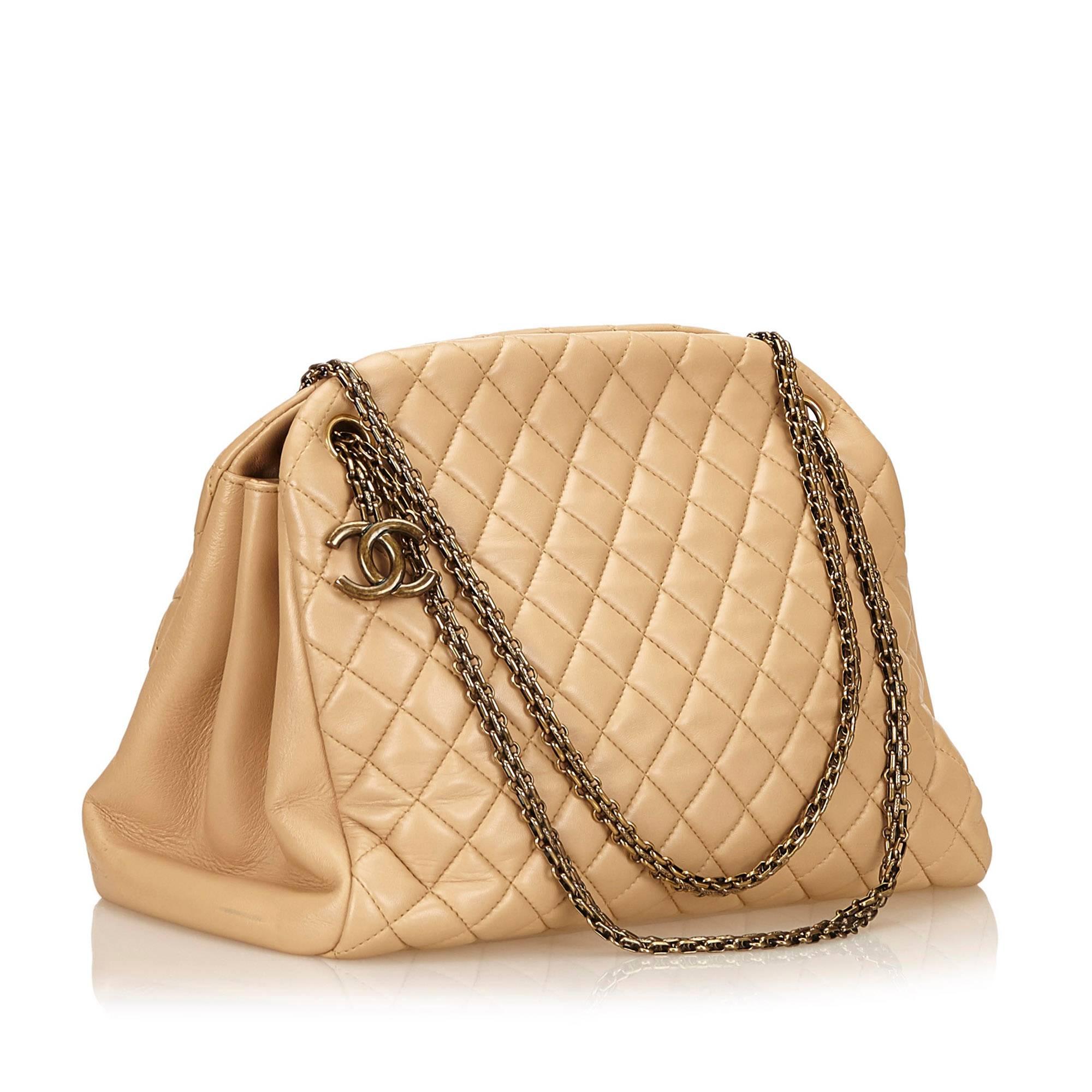 Product details:  Beige quilted leather Mademoiselle bowling bag by Chanel.  Dual chain shoulder straps.  Three main compartments- two open and center zip.  Lined interior with inner slide pockets and key fob.  Protective metal feet.  Antiqued