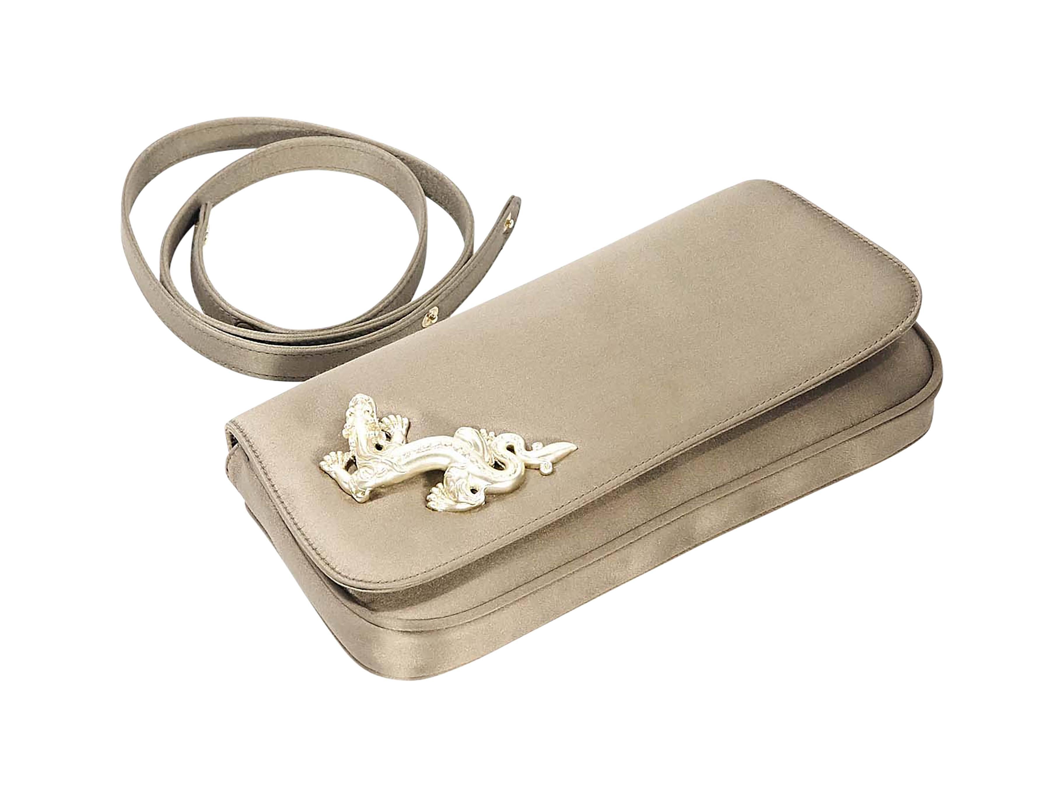 Product details: Bronze satin convertible clutch by Barry Kieselstein-Cord. Accented with a dragon charm. Detachable shoulder strap. Front flap with magnetic snap closure. Lined interior with inner slide pocket. Goldtone hardware. 9