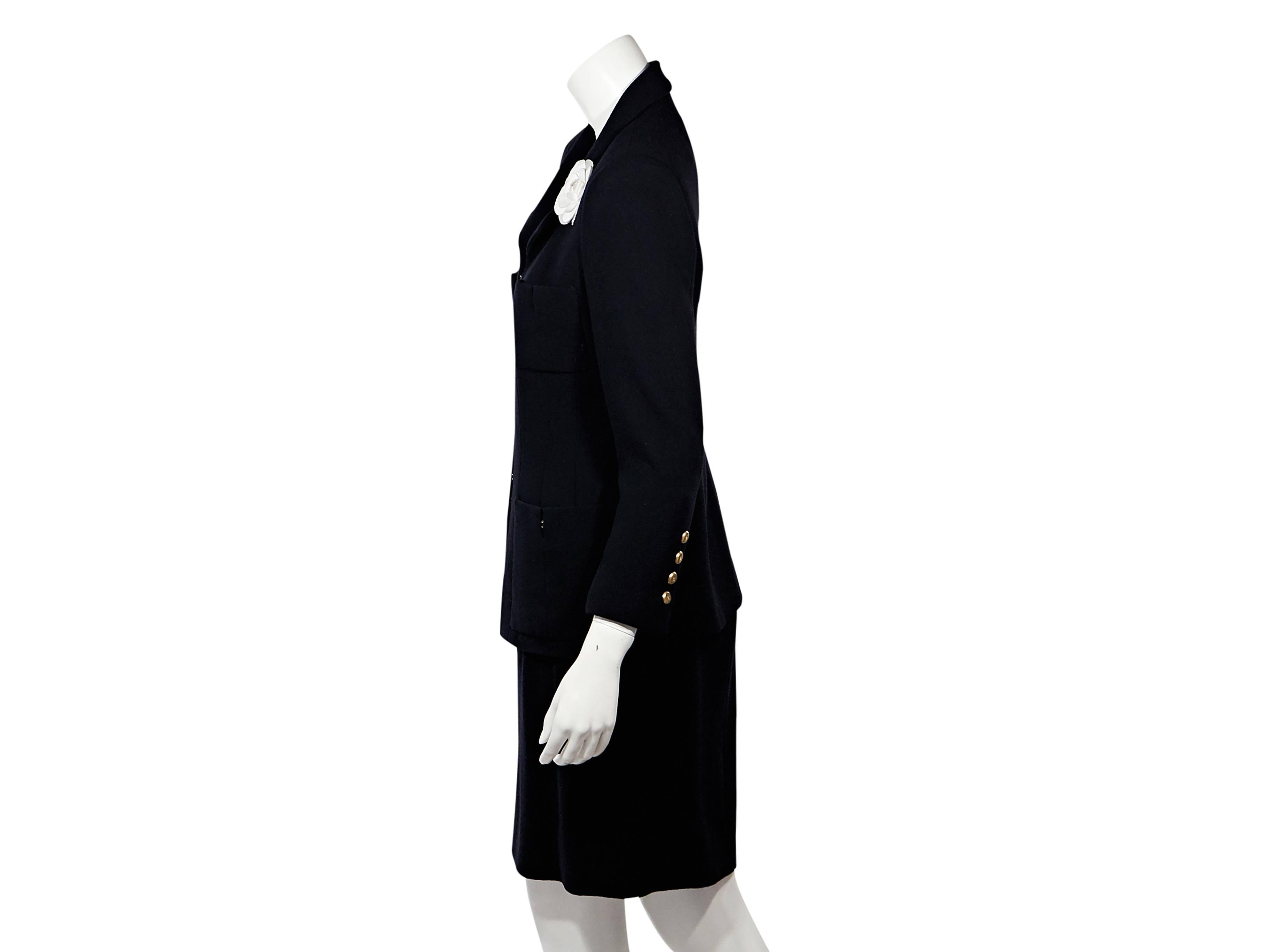 Product details: Navy wool skirt suit set by Chanel. Accented with a white floral applique. Notched lapels. Long sleeves. Hook-front closure. Four front patch pockets. Four-button detail at cuffs. Matching skirt. Banded waist.
Condition: Very good.
