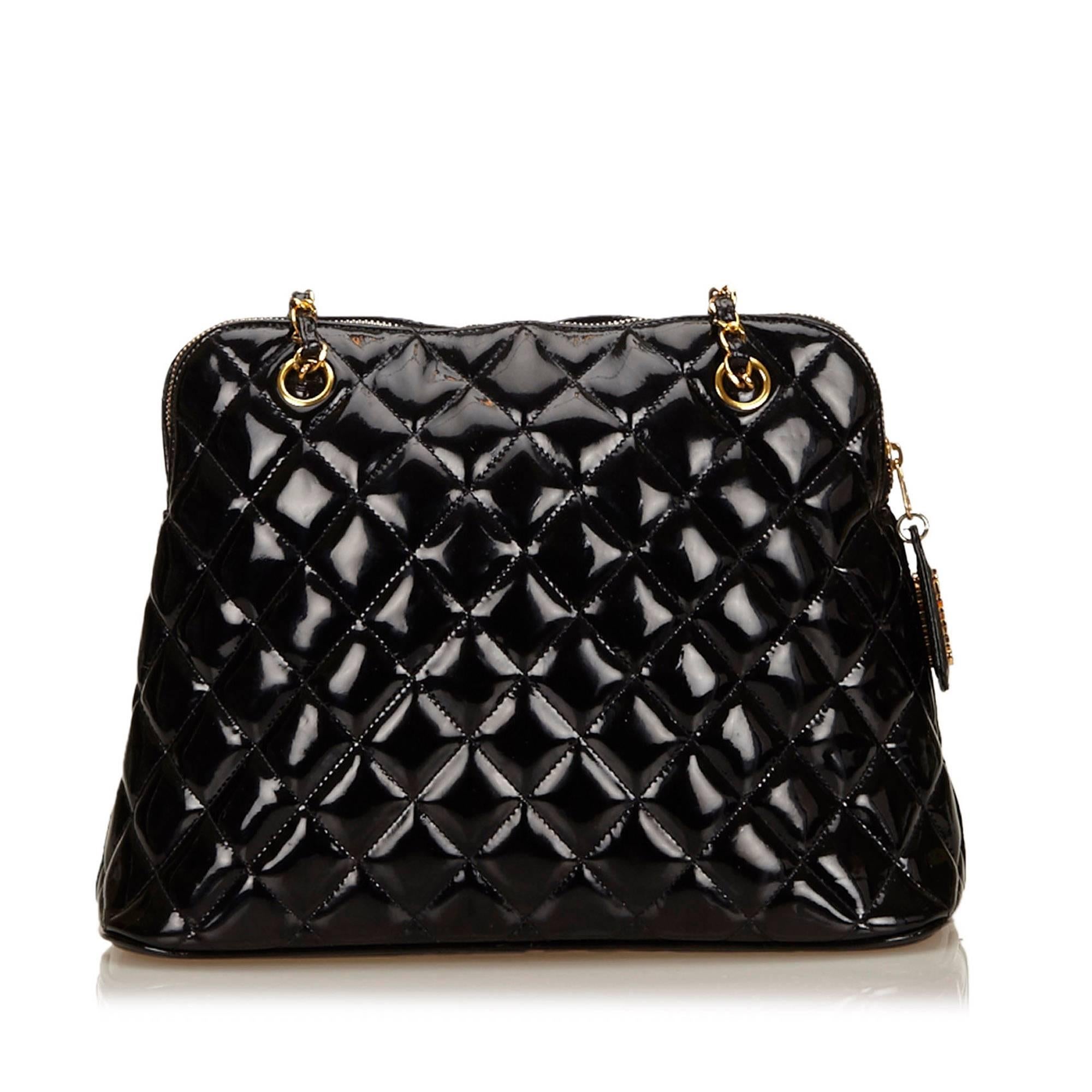 Product details: Black quilted Matelasse patent leather shoulder bag by Chanel. Dual chain and leather shoulder straps. Top zip closure. Leather lined interior with inner zip pocket. Logo embossed flat bottom. Goldtone hardware. Dust bag included.