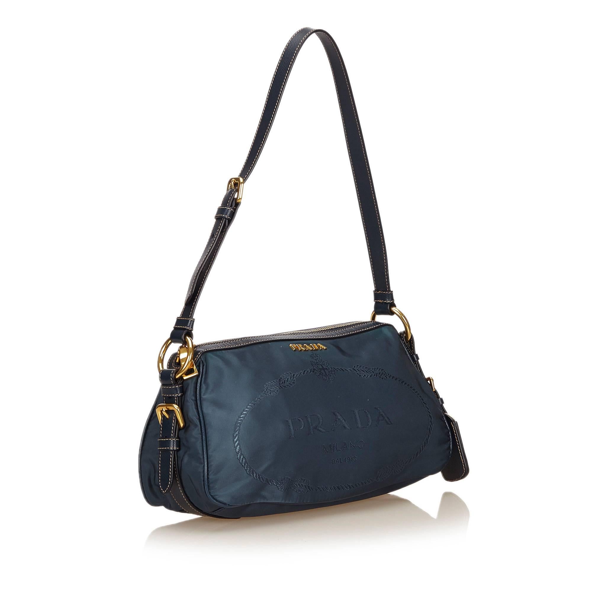 Product details:  Blue nylon shoulder bag by Prada.  Trimmed with leather.  Adjustable shoulder strap.  Top zip closure.  Lined interior with inner slide and zip pockets.  Goldtone hardware.  Authenticity card and dust bag included.  12