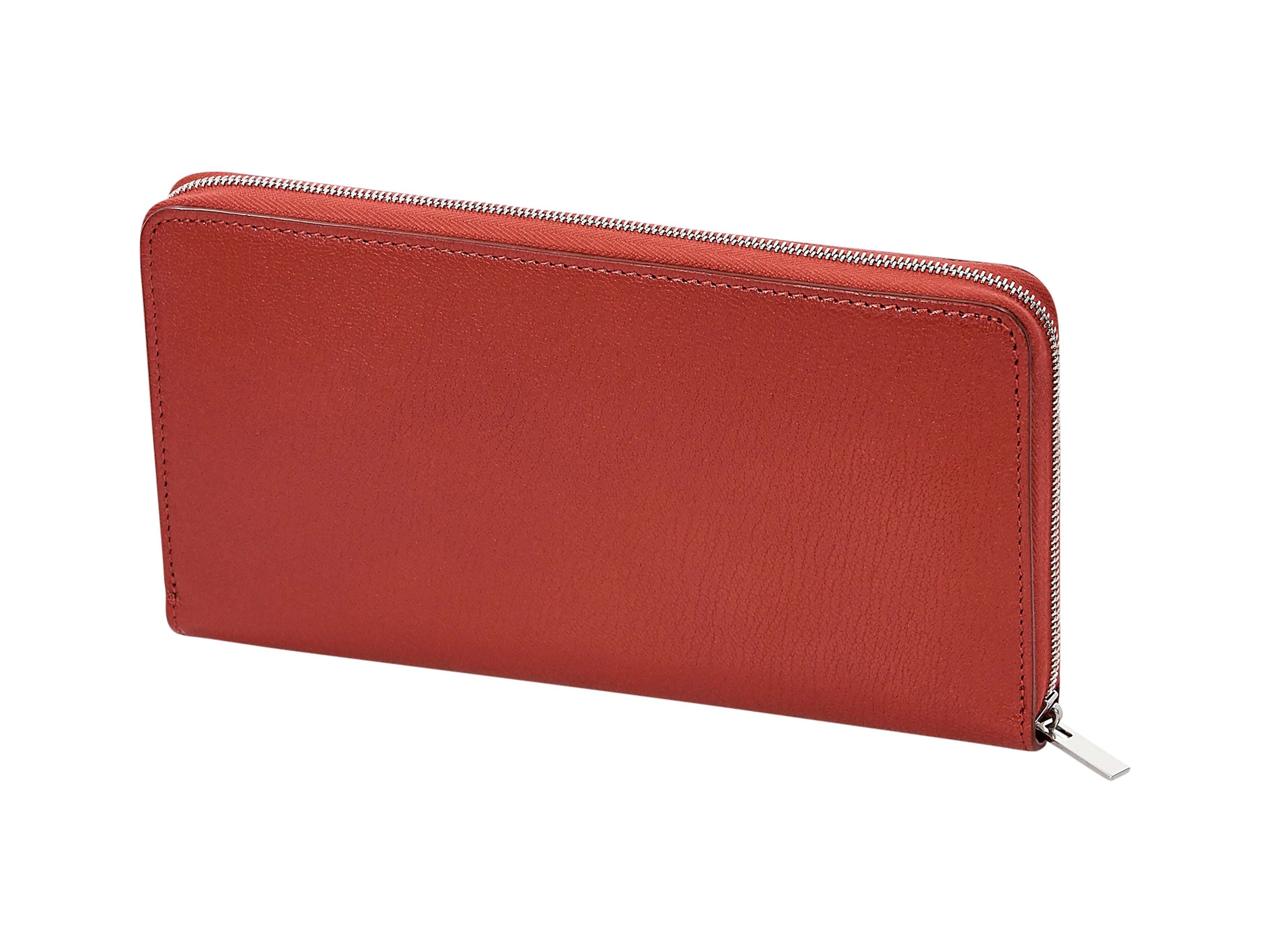 Product details:  Red leather large wallet by Céline.  Zip-around closure.  Leather lined interior with multiple credit card slots and center zip coin pouch.  Silvertone hardware.  7.5