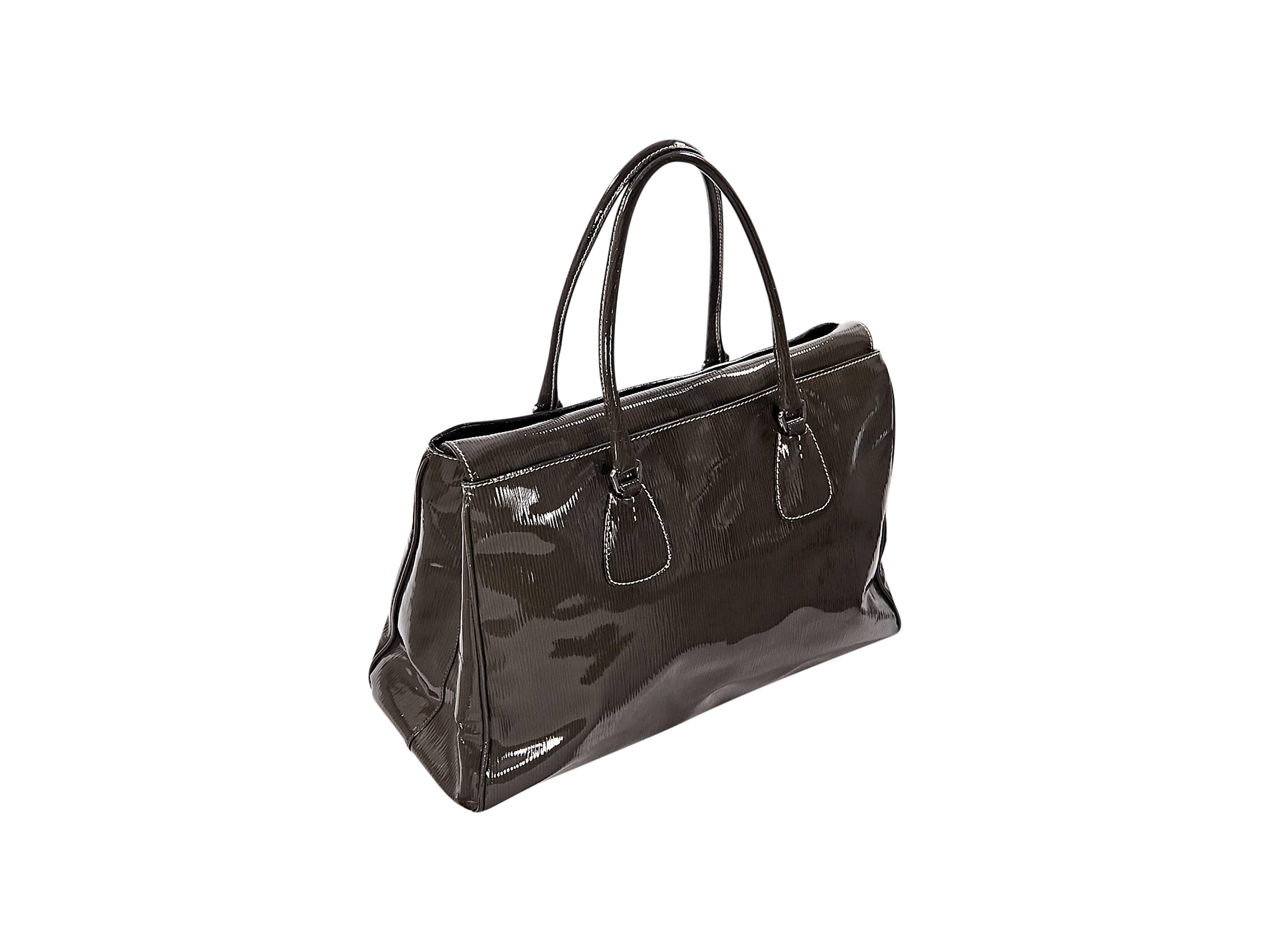 Product details:  Olive patent leather tote bag by Prada.  Dual shoulder straps.  Top magnetic snap tab closure.  Lined interior with center magnetic snap pocket.  Protective metal feet.  Silvertone hardware.  17
