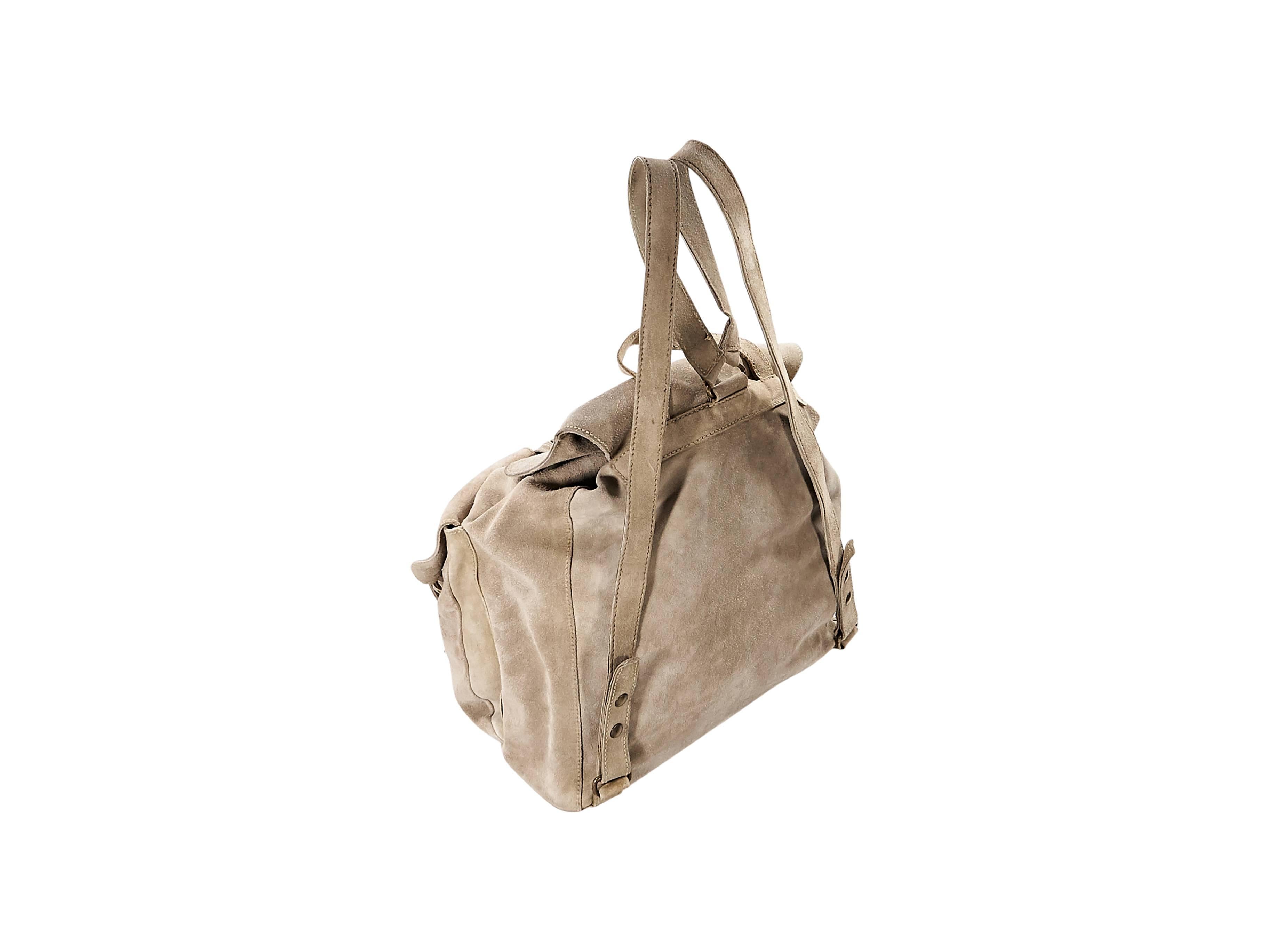 Product details:  Tan suede backpack by Prada.  Top carry handle.  Shoulder straps.  Drawstring closure under front flap with buckle closure.  Front exterior buckle flap pockets.  Lined interior with inner zip pocket.  Antiqued goldtone hardware. 