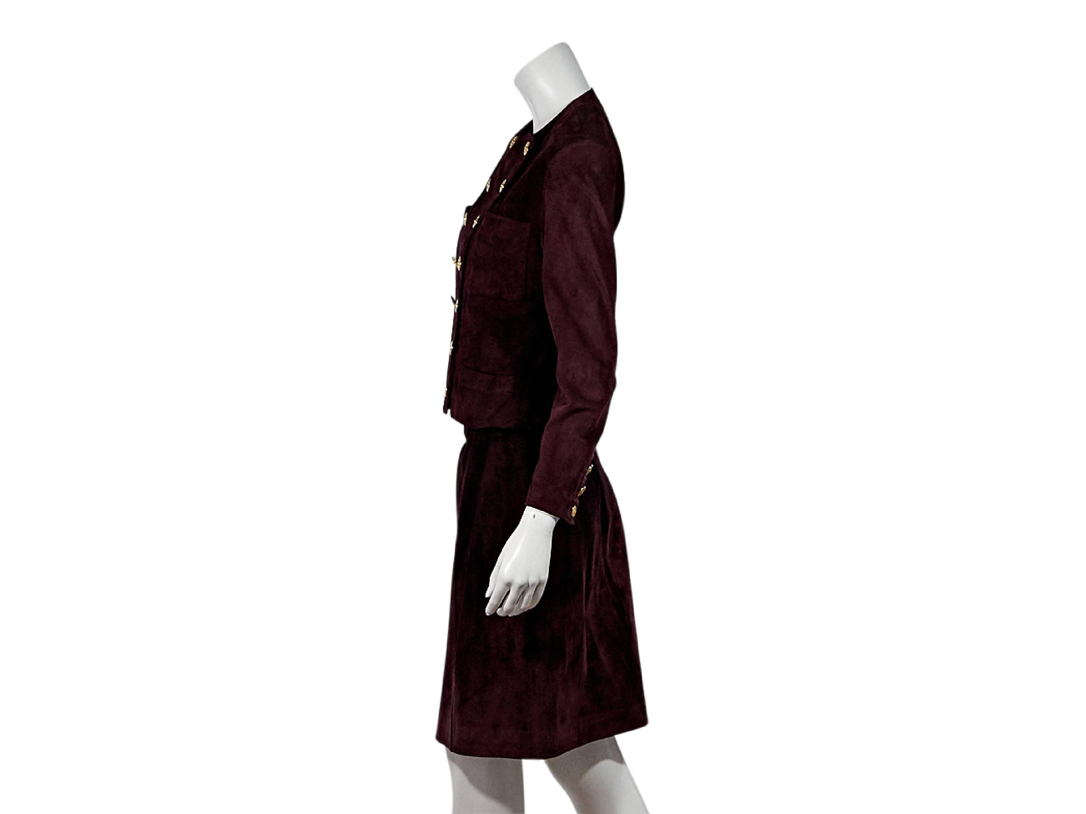 Product details:  Burgundy suede skirt suit set by Chanel.  Crewneck.  Bracelet-length sleeves.  Three-button detail at cuffs.  Double-breasted button front.  Chest and waist patch pockets.  Matching pencil skirt.  Banded waist.  Concealed back zip