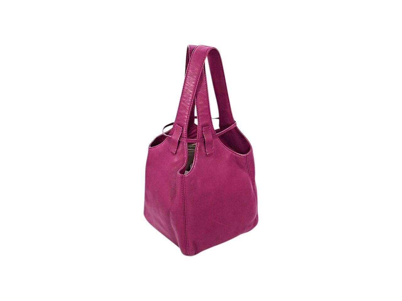 Product details:  Magenta leather bucket bag by Loro Piana.  Crisscross shoulder straps.  Tie closure with hanging lock and charm.  Lined interior with inner zip pocket.  Goldtone hardware.  7