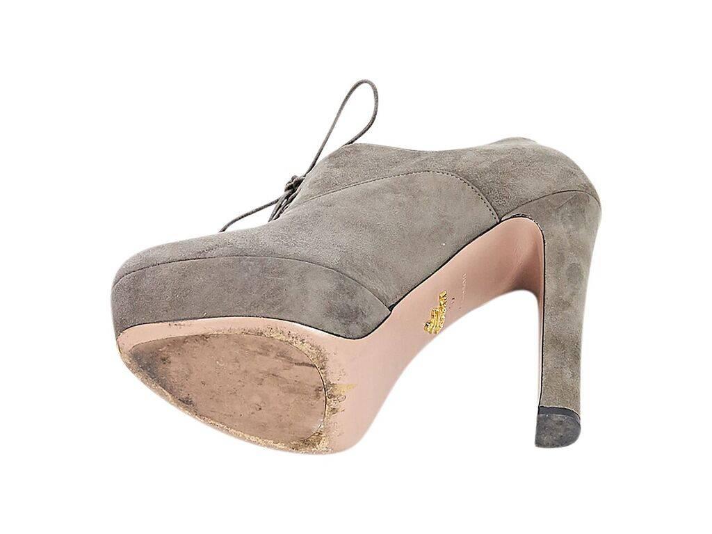 Product details:  Grey suede platform ankle boots by Prada.  Lace-up closure.  Round toe.  Towering heel and platform design.  
Condition: Pre-owned. Very good.
Est. Retail $ 698.00