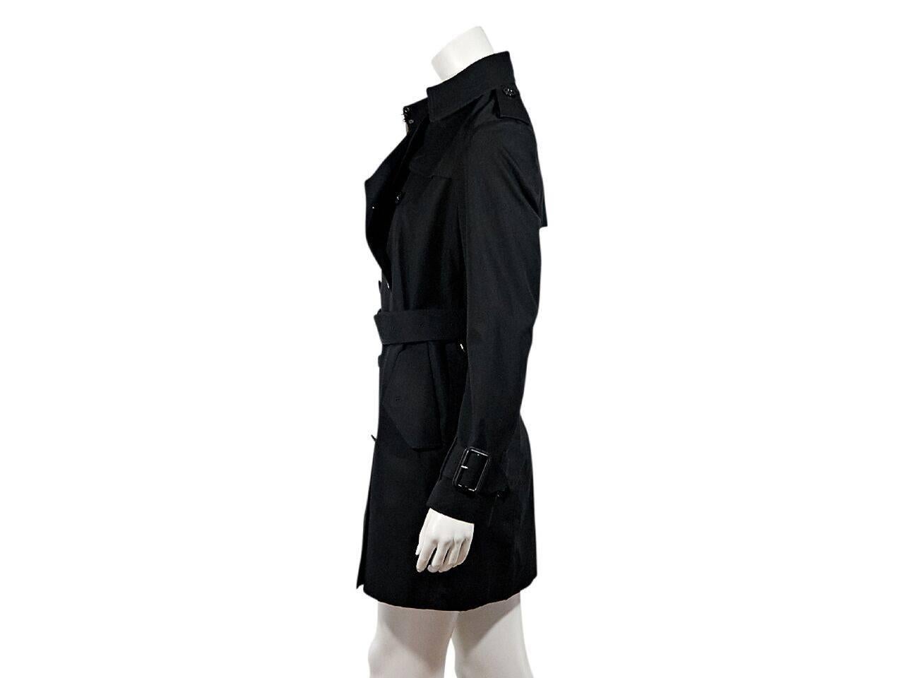 Product details:  Black trench coat by Burberry.  Spread collar.  Notched lapel.  Button shoulder epaulettes.  Long sleeves.  Adjustable belted cuffs.  Double-breasted button closure.  Adjustable belted waist.  Waist button flap pockets.  Back storm