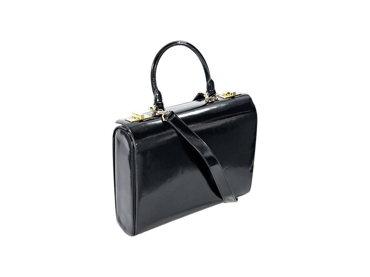 Product details:  Black patent leather briefcase by Simone Rocha.  Top carry handle.  Detachable, adjustable crossbody strap.  Double twist-lock closure.  Lined interior with inner slide pocket and attached zip pouch.  Protective metal feet. 