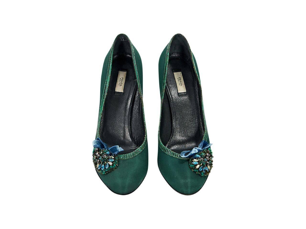 Product details:  Emerald green satin pumps by Prada.  Lizard skin trim.  Bejeweled detail accents vamp.  Round toe.  Slip-on style. 
Condition: Pre-owned. Very good.
Est. Retail $ 428.00