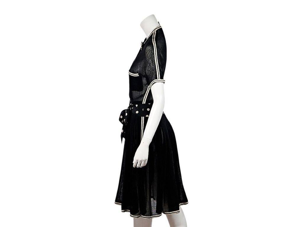 Product details:  Vintage black semi-sheer dress by Chanel.  Crewneck accented with a bow.  Short sleeves.  Chest patch pockets.  Polka-dot self-tie belted waist. 
Condition: Pre-owned. Very good.
Est. Retail $ 1,750.00