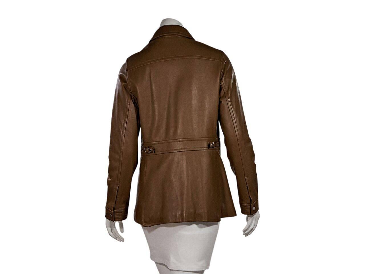 Product details:  Tan leather jacket by Coach. Point collar.  Long sleeves.  Single button cuffs.  Concealed front closure.  Waist slide pockets.   Side waist buckle accents.  Silvertone hardware. 
Condition: Pre-owned. Very good.
Est. Retail $