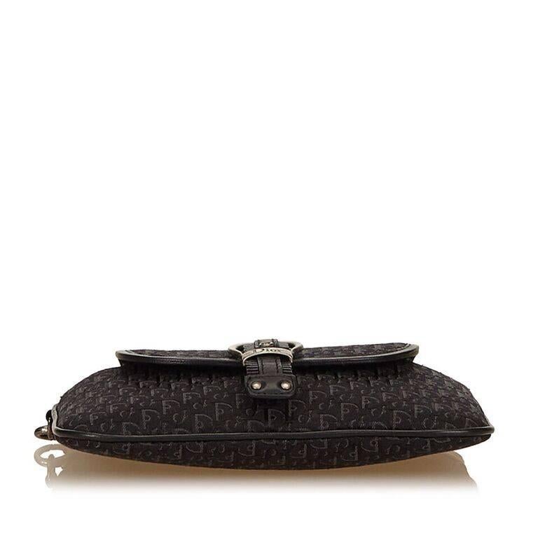 Product details:  Black jacquard Diorissimo wristlet by Christian Dior.  Trimmed with leather.  Wristlet strap.  Top zip closure.  Front flap pocket with buckle strap.  Lined interior.  Antiqued silvertone hardware.  Authenticity card and dust bag