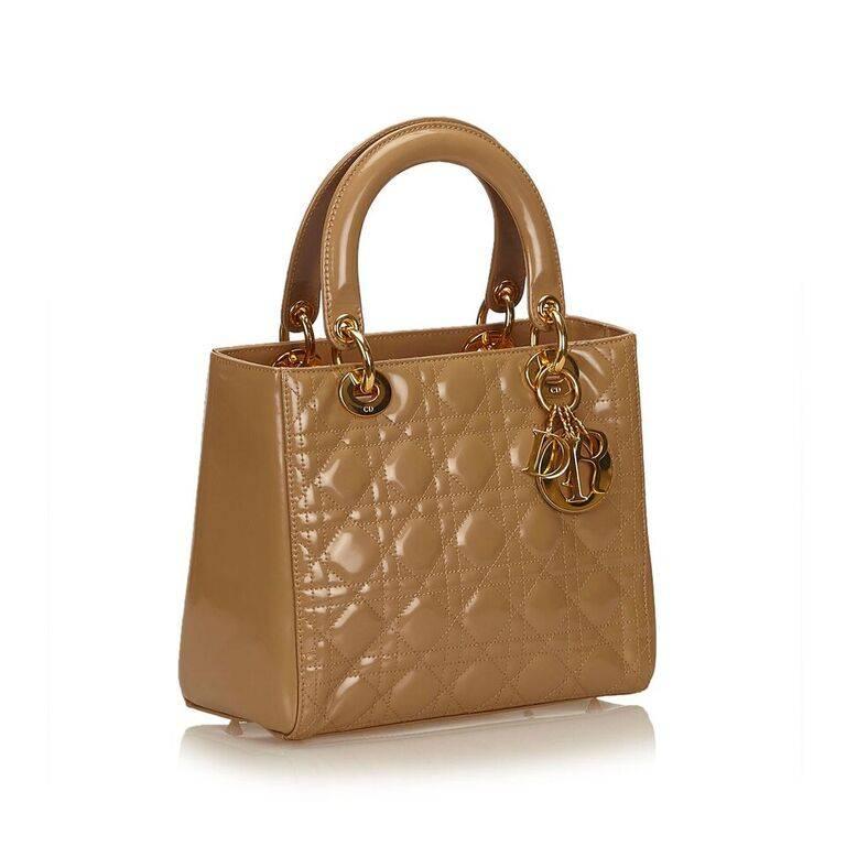 Product details:  Tan quilted patent leather Lady Dior bag by Christian Dior.  Dual carry handles.  Top zip closure.  Lined interior with inner zip pocket.  Protective metal feet.  Goldtone hardware.  Authenticity card included.  9