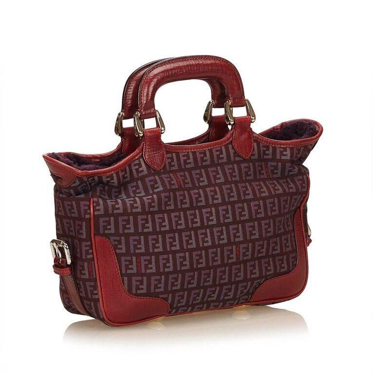 Product details:  Red jacquard canvas Zucchino satchel by Fendi.  Trimmed with leather.  Dual carry handles.  Adjustable, detachable crossbody bag.  Top zip closure.  Lined interior with inner slide pocket.  Protective metal feet.  Goldtone