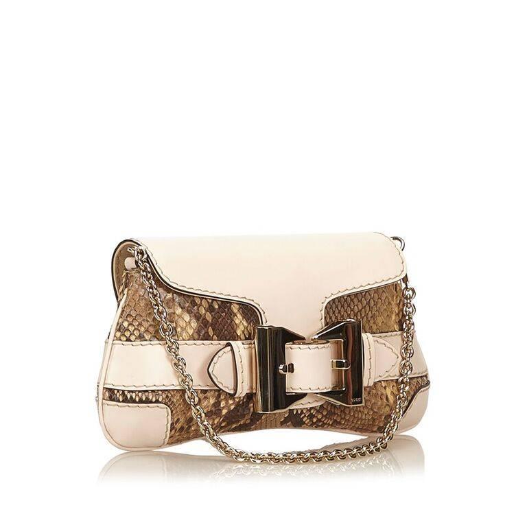 Product details:  Beige python and leather shoulder bag by Gucci.  Tuck-away chain shoulder strap.  Front flap with tab closure.  Front accented with buckle detail.  Lined interior with inner slide pocket.  Goldtone hardware.  11