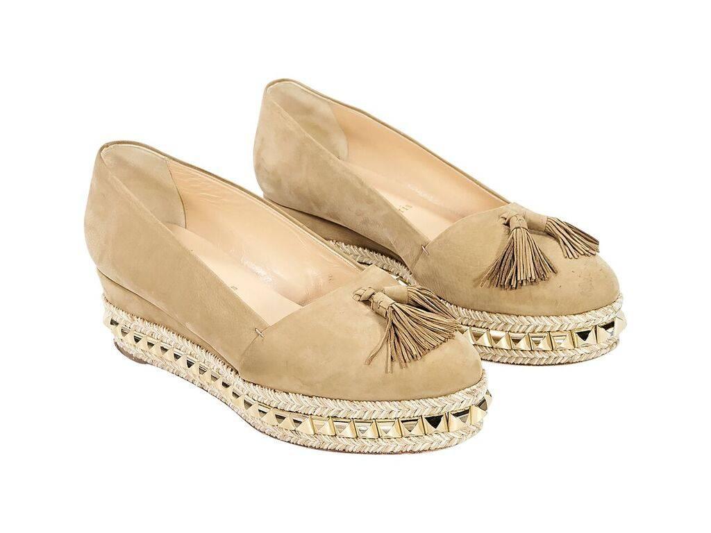 Product details:  Tan suede wedge espadrilles by Christian Louboutin.  Trimmed with pyramid studs.  Tassels accent vamp.  Round toe.  Slip-on style.  Goldtone hardware. 
Condition: Pre-owned. Very good.
Est. Retail $ 1,000.00