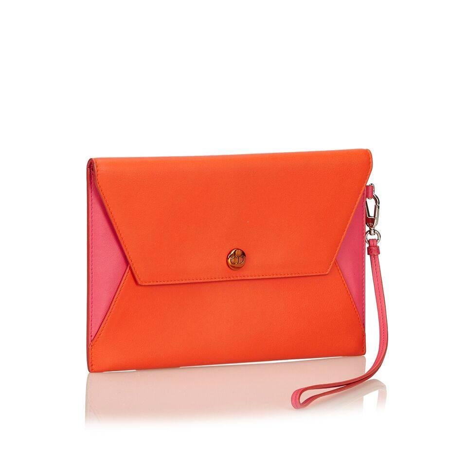 Product details:  Orange and pink leather wristlet by Christian Dior.  Detachable wristlet strap.  Front flap with snap closure.  Silvertone hardware.  6
