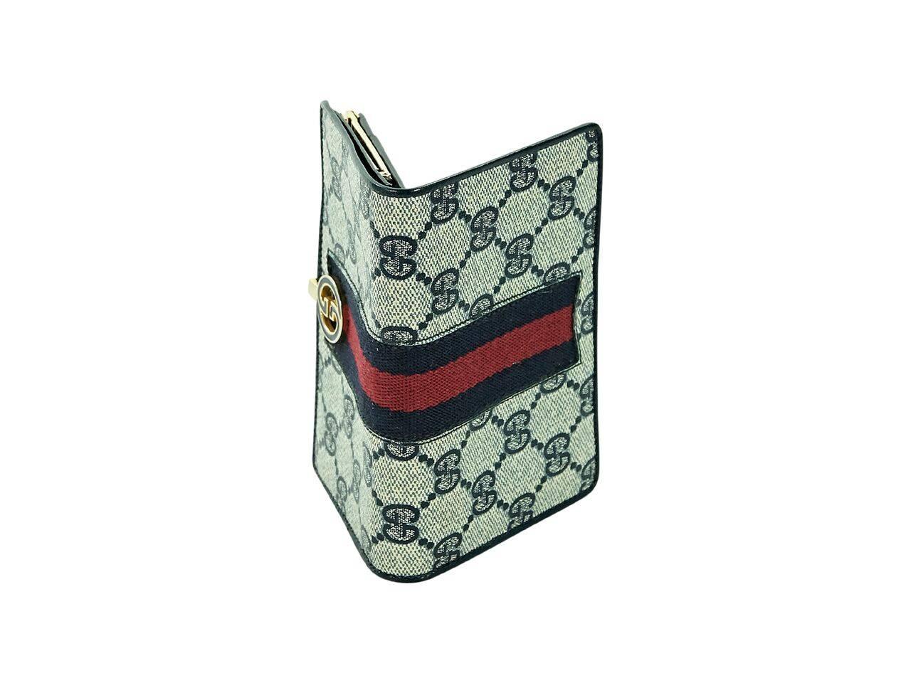 Product details:  Vintage black GG canvas wallet by Gucci.  Accented with a center red and black stripe.  Snap closure.  Leather lined interior with credit card slots.  Top clasp close coin pouch.  Goldtone hardware.  5.25