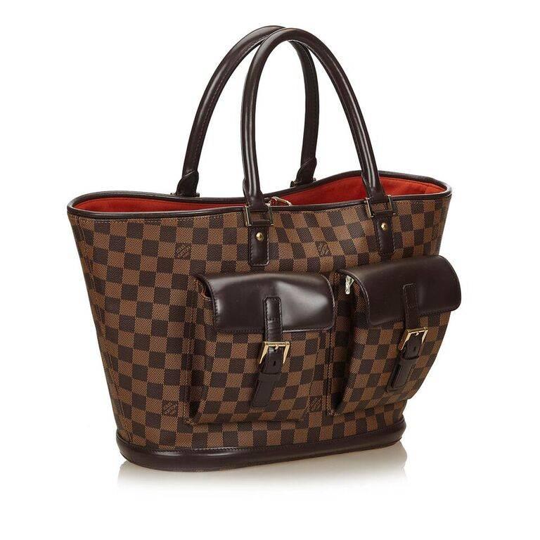 Product details:  Brown damier ebene canvas Manosque GM tote bag by Louis Vuitton.  Dual carry handles.  Trimmed with leather.  Top hook closure.  Lined interior with inner zip pockets.  Front buckle flap pockets.  Goldtone hardware.  21"L x