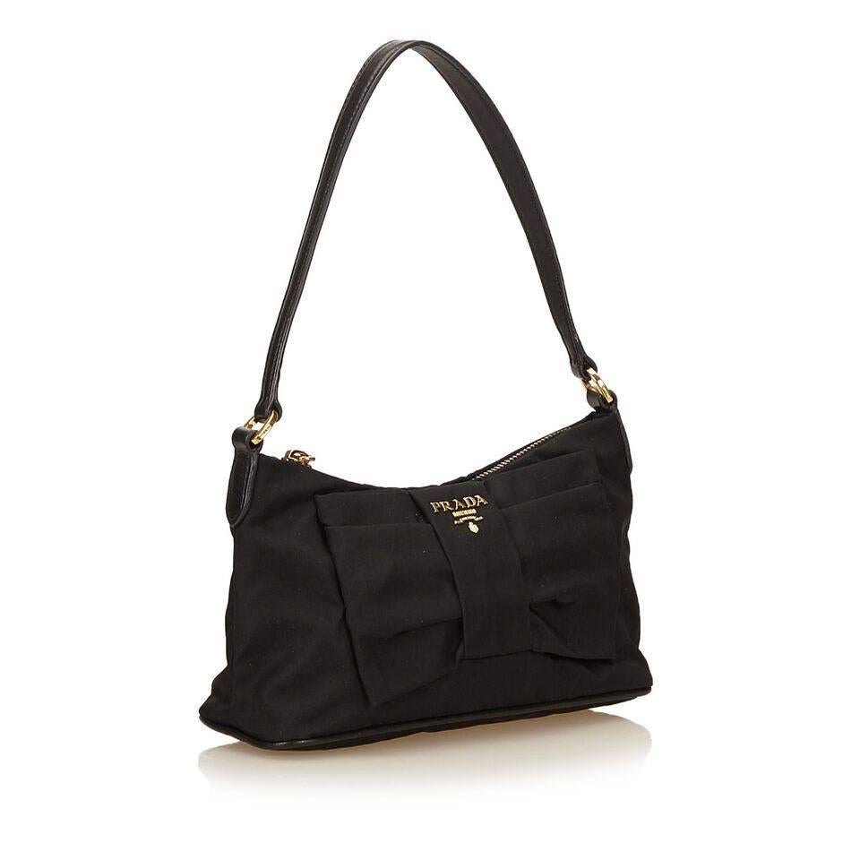 Product details:  Black nylon shoulder bag by Prada.  Flat bow accents front.  Single shoulder strap.  Top zip closure.  Lined interior.  Goldtone hardware.  8