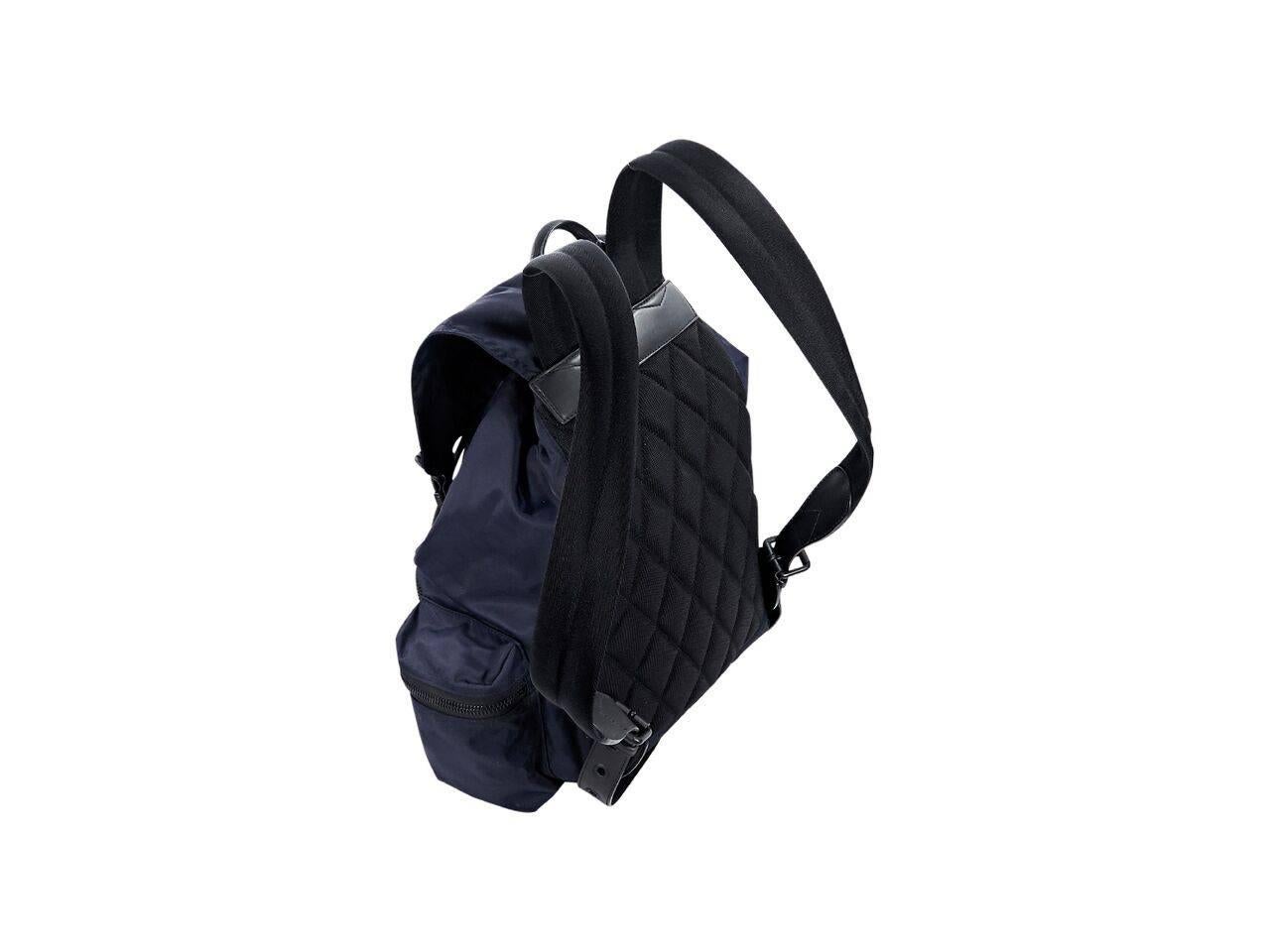 Product details:  Navy blue nylon backpack by Burberry.  Trimmed with black saffiano leather.  Top carry handle.  Adjustable shoulder straps.  Drawstring closure under front flap.  Concealed magnetic snap closures.  Lined interior with inner zip and