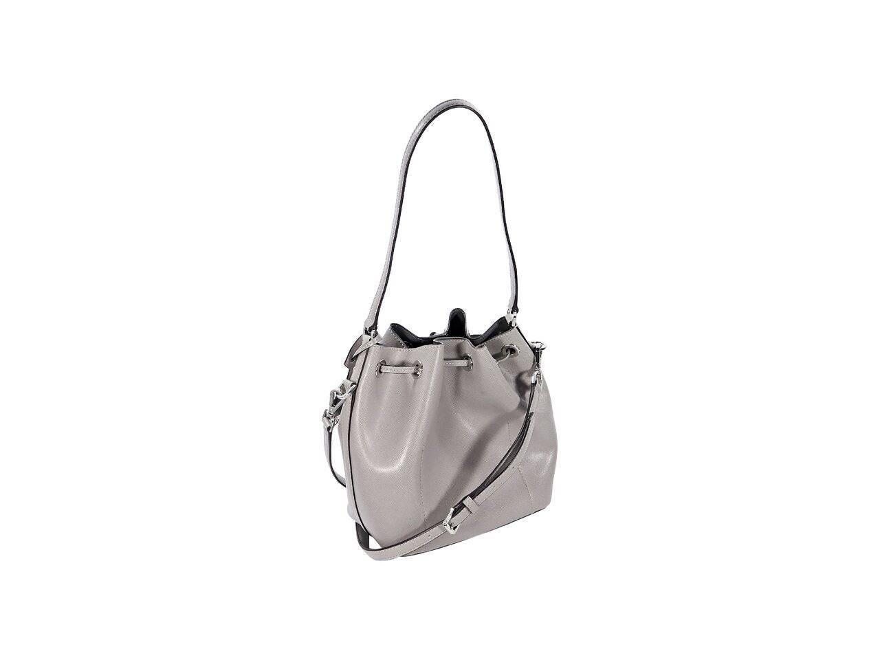 Product details:  Grey saffiano leather bucket bag by Michael Kors.  Shoulder strap.  Adjustable, detachable crossbody strap.  Drawstring and magnetic snap closure.  Inner slide pocket.  Front exterior pocket.  Protective metal feet.  Silvertone