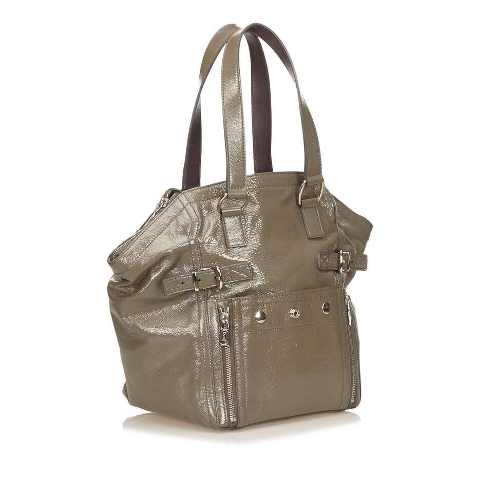 Product details:  Olive green patent leather Downtown tote bag by Yves Saint Laurent.  Dual shoulder straps.  Dual zip and open top closure.  Lined interior with inner zip pocket.  Exterior buckle and zip details.  Protective metal feet.  Silvertone