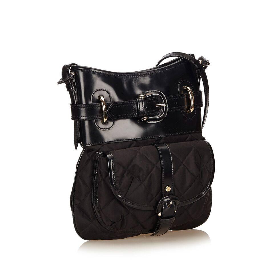 Product details:  Black quilted nylon crossbody bag by Burberry.  Accented with leather.  Top buckle strap detail.  Adjustable crossbody strap.  Top zip closure.  Lined interior with inner zip and slide pockets.  Front exterior buckle flap pocket. 