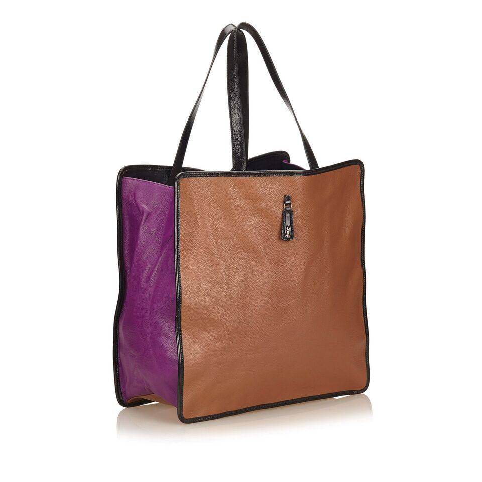 Product details:  Tan and purple leather tote bag by Yves Saint Laurent.  Dual shoulder straps.  Open top.  Lined interior with inner zip and slide pockets.  Goldtone hardware.  15"L x 14"H x 8"D.
Condition: Pre-owned. Very good.
Est.