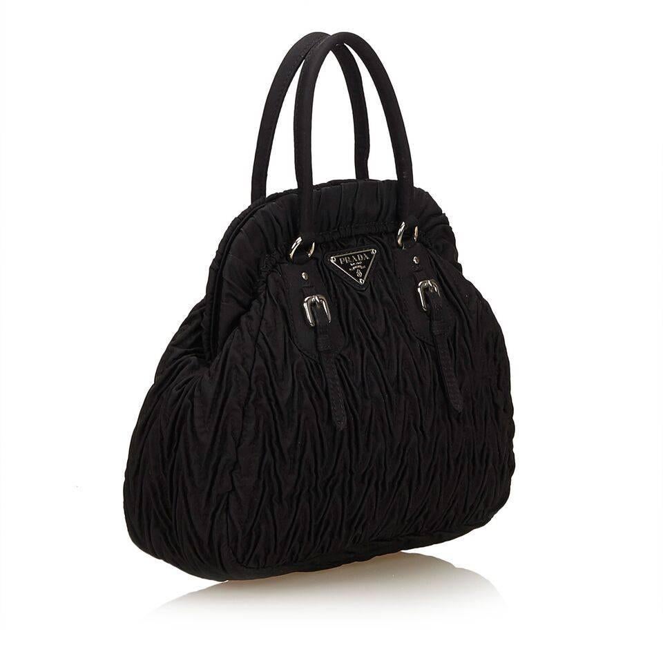 Product details:  Black gathered nylon handbag by Prada.  Top carry handles.  Hinged top with magnetic snap closure.  Lined interior with inner slide pocket.  Silvertone hardware.  7"L x 7"H x 3"D.
Condition: Pre-owned. Very