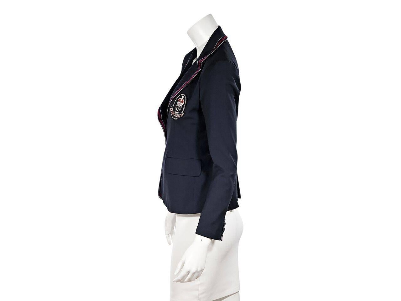 Product details:  Navy blue schoolboy blazer by Libertine.  Red grosgrain trim.  Notched lapel.  Long sleeves.  Four-button detail at cuffs.  Button-front closure.  Patch detail at chest.  Waist flap pockets.  Center back inverted hem.
Condition: