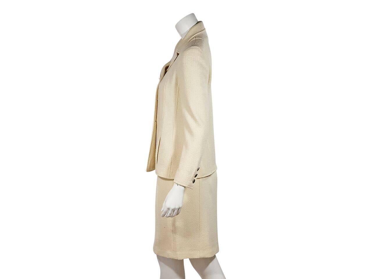 Product details:  Ivory wool-blend skirt suit set by Chanel.  Notched lapel.  Long sleeves.  Three-button detail at cuffs.  Double-breasted button front.  Waist slide pockets.  Matching pencil skirt. Banded waist.  Concealed back zip closure. Label