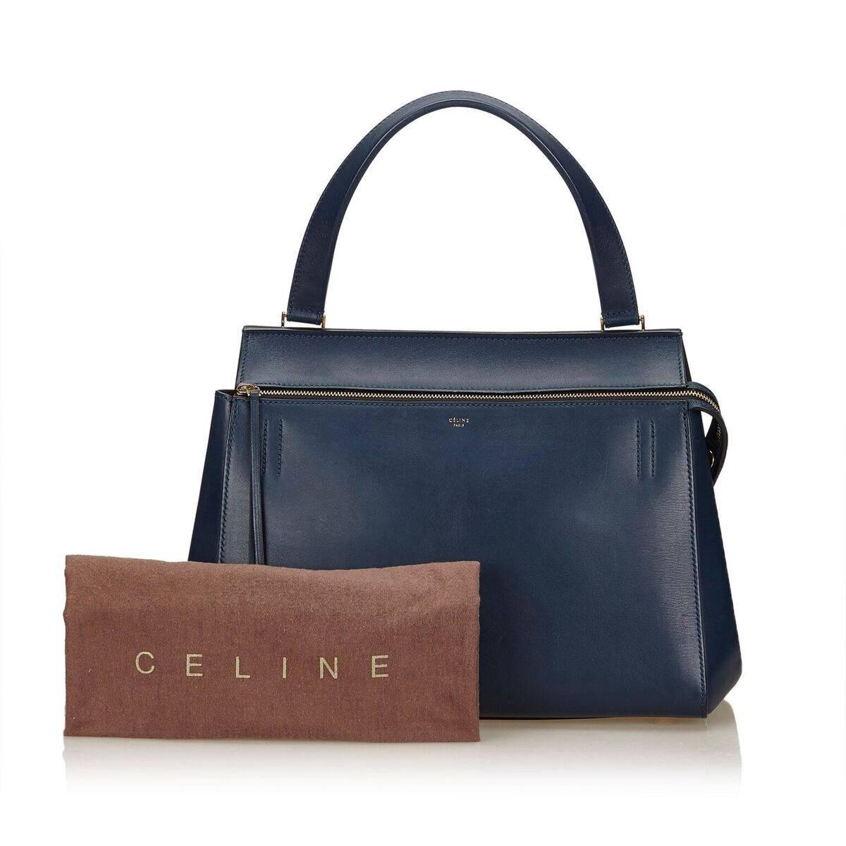 Product details:  Navy blue large leather Edge top-handle bag by Celine.  Top zip closure.  Leather interior with inner slide pockets.  Back exterior snap pocket.  Protective metal feet.  Goldtone hardware.  Dust bag included.  11