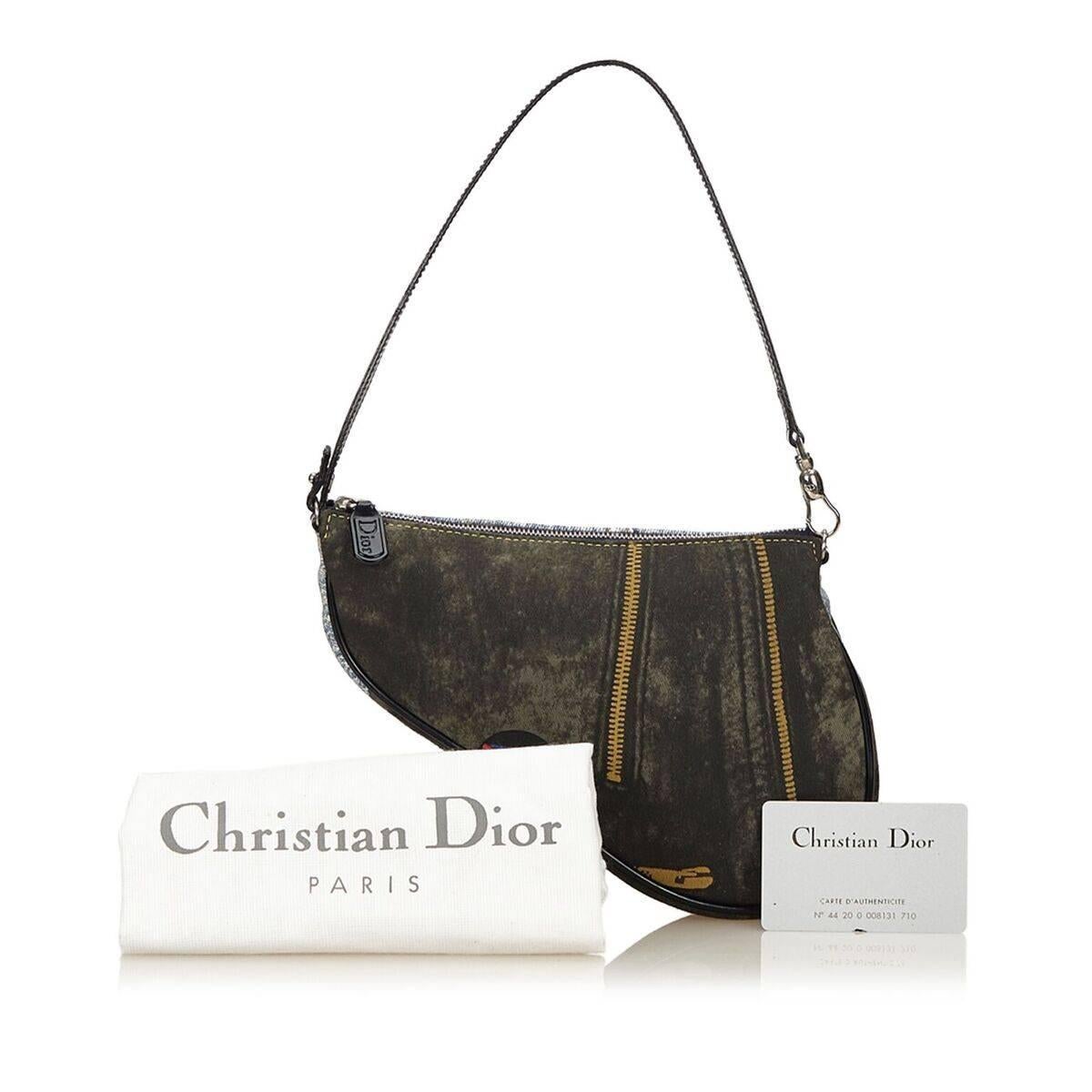 Product details:  Multicolor denim mini saddle bag by Christian Dior.  Trimmed with leather.  Printed and patch design.  Single shoulder strap.  Top zip closure.  Lined interior.  Authenticity card and dust bag included.  Silvertone hardware.  9