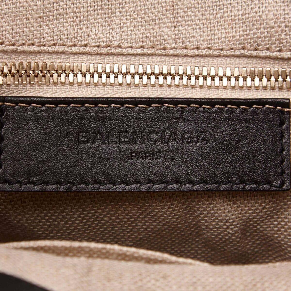 Product details:  Black leather and tan canvas satchel by Balenciaga.  Trimmed with brown python skin.  Top carry handles.  Detachable, adjustable crossbody strap.  Open top.  Lined interior with inner zip and open pockets.  Front exterior flap