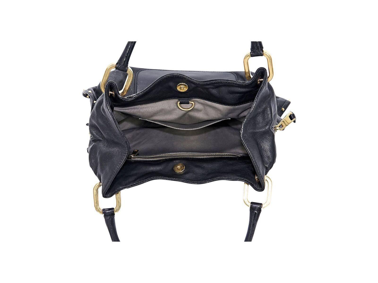 Product details:  Black leather shoulder bag by Marc Jacobs.  Pyramid studded trim.  Dual shoulder straps.  Magnetic snap closure.  Lined interior with inner zip and slide pockets.  Front exterior slide pocket accented with a padlock.  Side zippers.