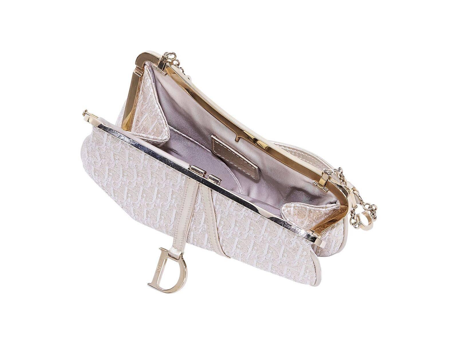 Product details:  Metallic champagne mini saddle bag by Christian Dior.  Hanging logo charm.  Single shoulder strap.  Top pin closure.  Lined interior with inner slide pocket.  Goldtone hardware.  7.5