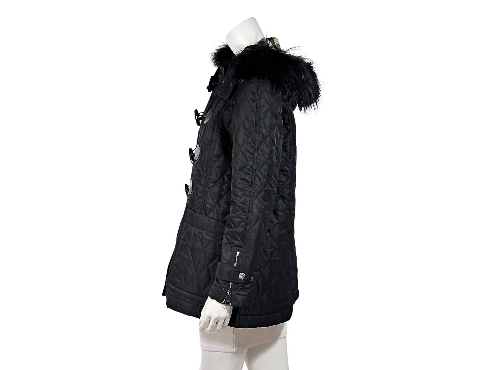 Product details:  Black quilted hooded jacket by Burberry Brit.  Fur-trimmed hood.  Long sleeves.  Snap tab over zip cuffs.  Toggle front closure.  Waist slide pockets.  40