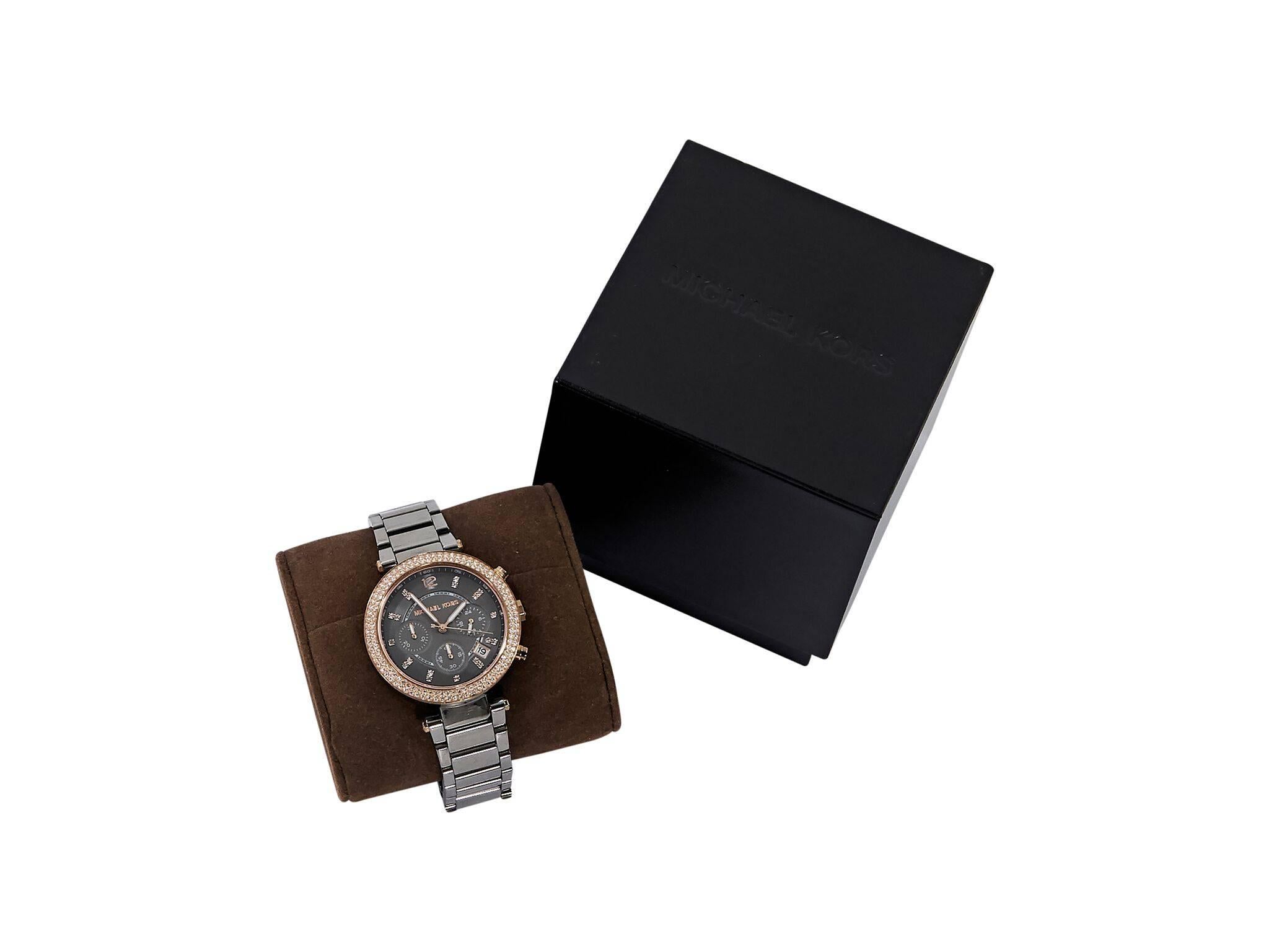 Product details:  Gunmetal-tone stainless steel watch by Michael Kors.  Rose gold-tone bezel embellished with crystals.  Hour, minute and second hands.  Crystal hour markers and Arabic numeral 12:00.  Date display between 4:00 and 5:00.  Three