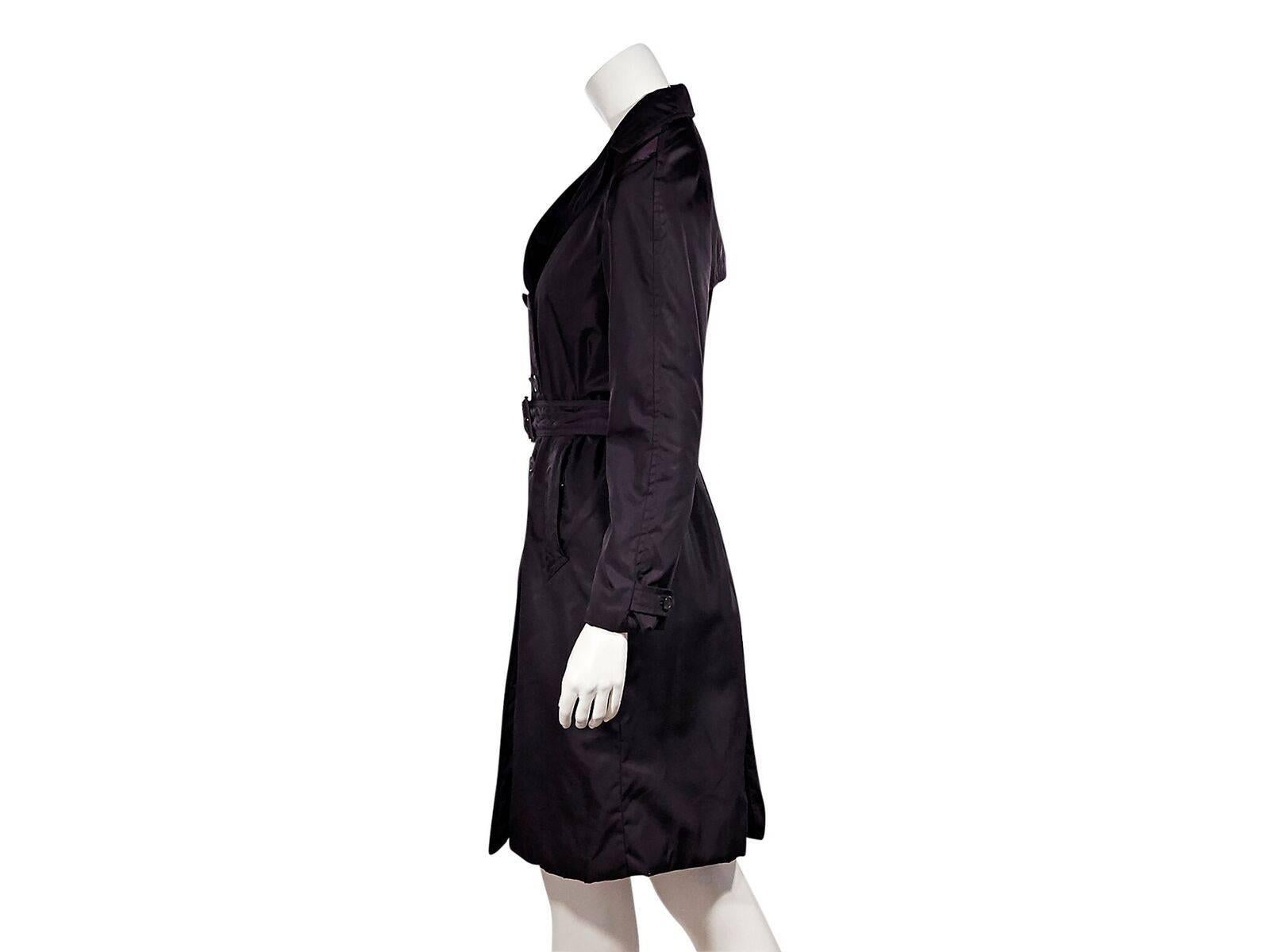 Product details:  Purple trench coat by Prada.  Notched lapel.  Long sleeves.  Button tab at cuffs.  Double-breasted button-front closure.  Adjustable belted waist.  Waist slide pockets.  Back storm vent.  Button back center hem vent.  Label size IT