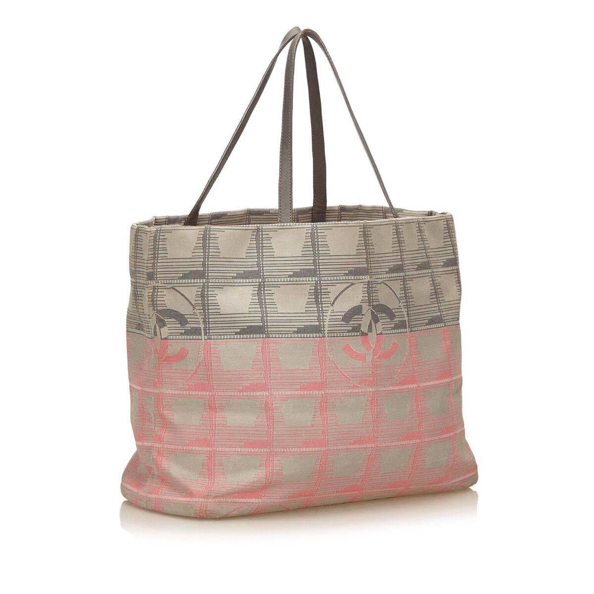 Product details:  Pink and grey jacquard New Travel Line tote bag by Chanel.  Dual shoulder straps.  Open top.  Lined interior with inner zip pocket and attached key fob.  Protective metal feet.  Silvertone hardware.  11